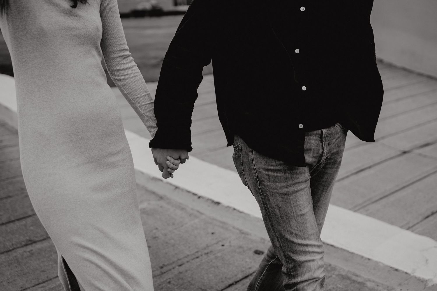 Black and white image of two people walking together on a paved path.