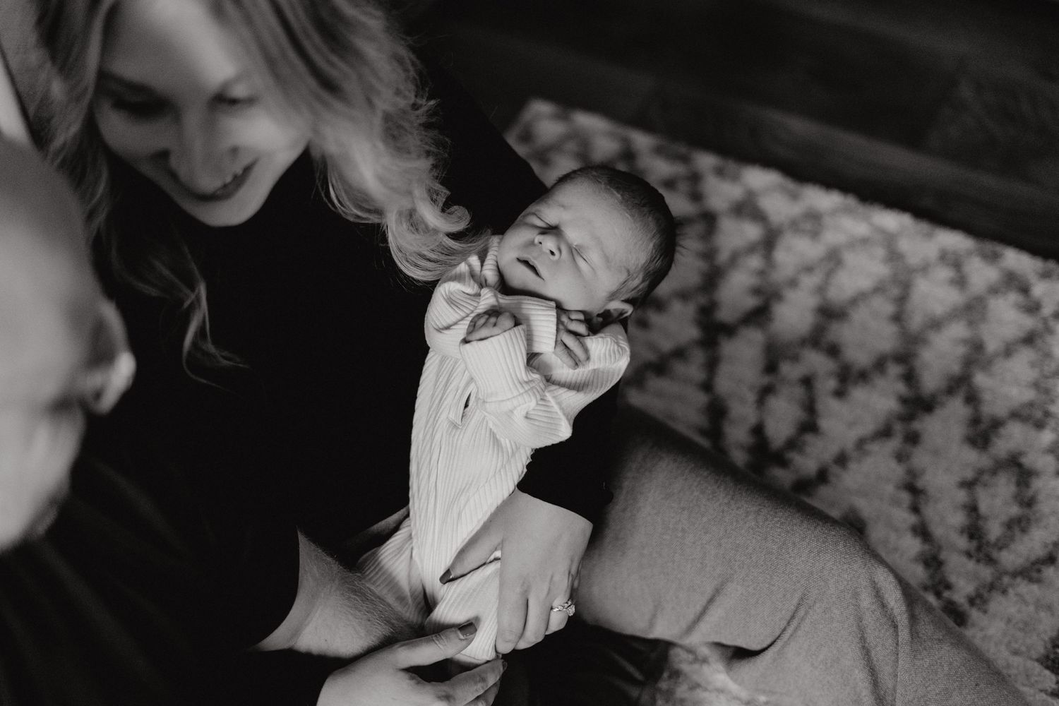 Candid family moment captured on patterned carpet in natural light.