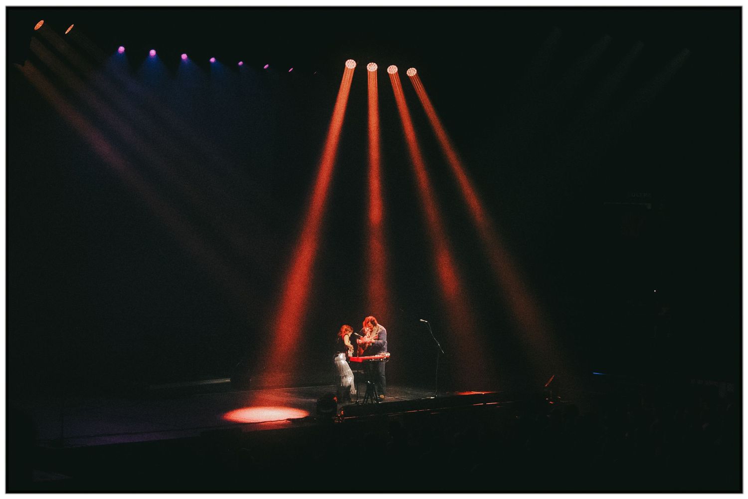 A series of stage lighting photos showing red and blue spotlights illuminating a dark performance space.