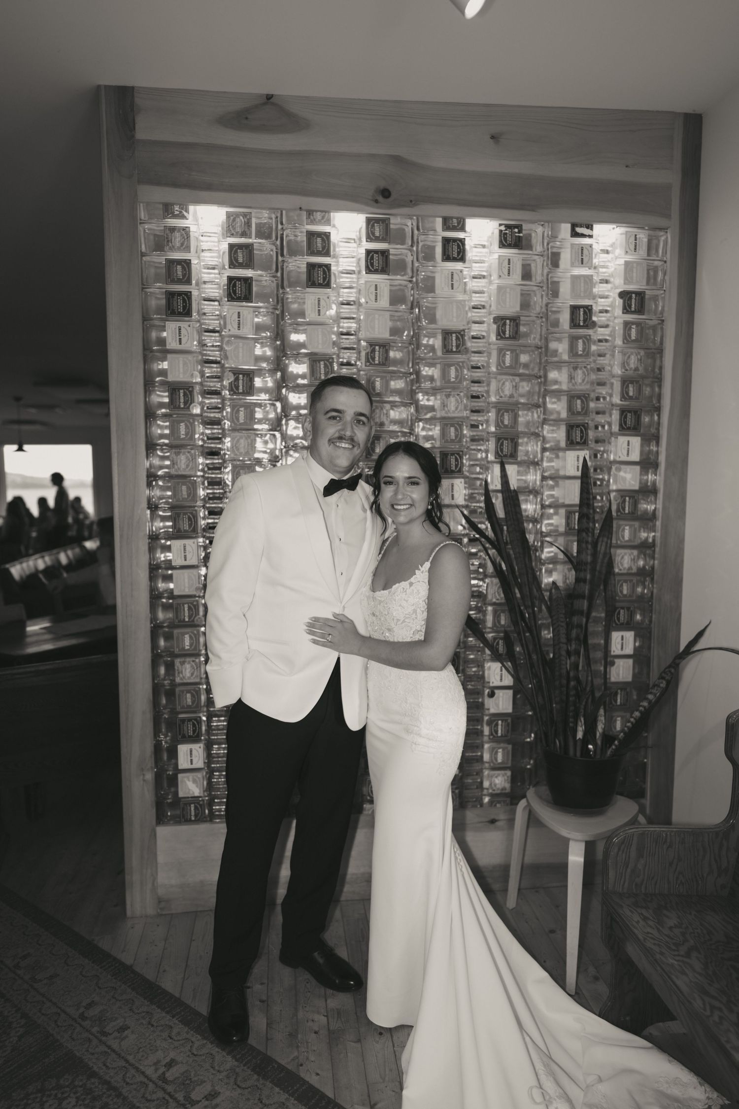 A black and white photo series showing a couple in wedding attire posing together in front of a wall display.