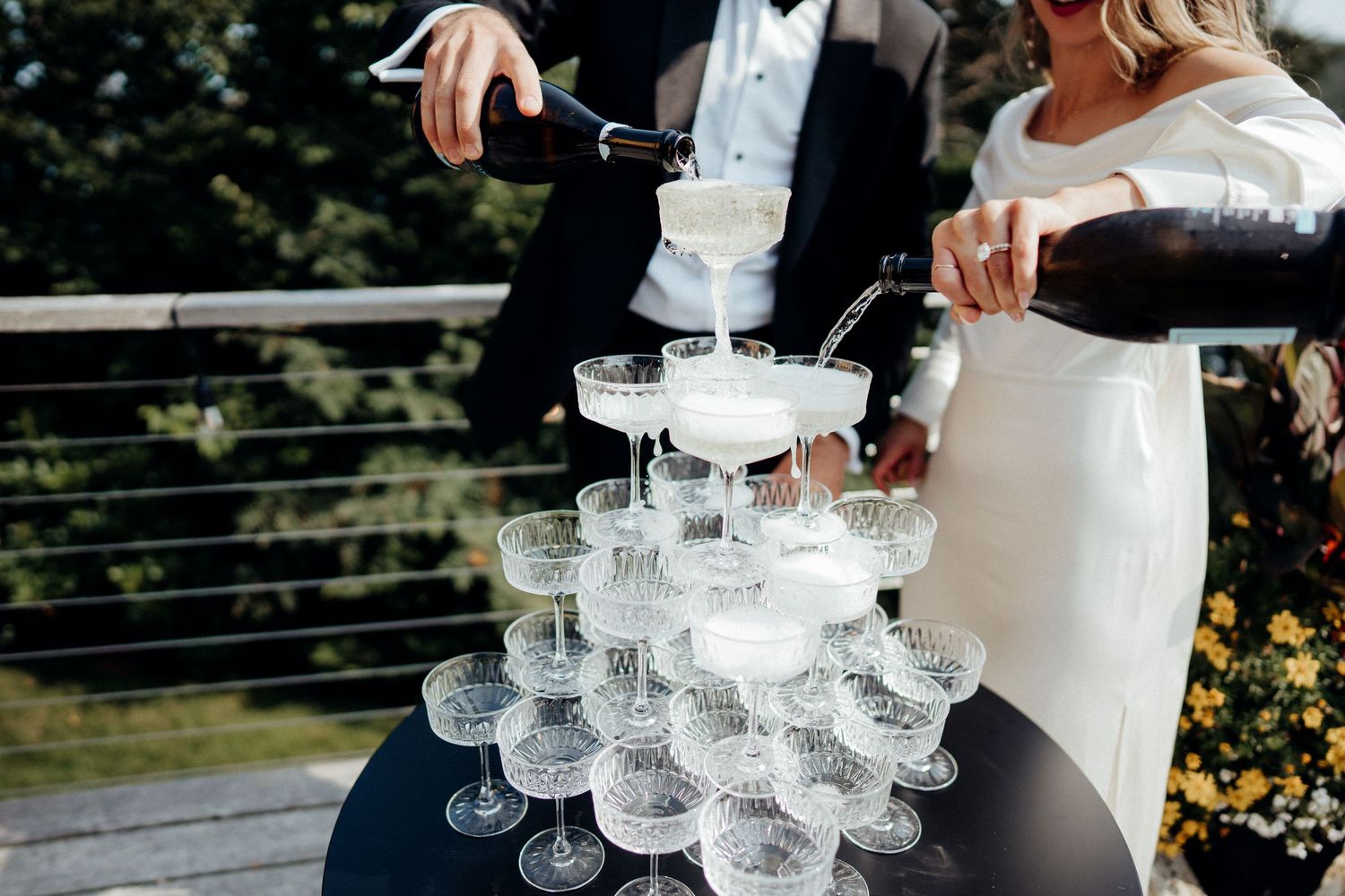 A champagne tower being carefully filled with bubbly at an elegant wedding celebration.