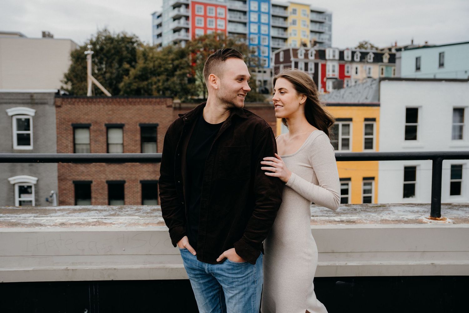 Two people walking together on a rooftop with cityscape views.