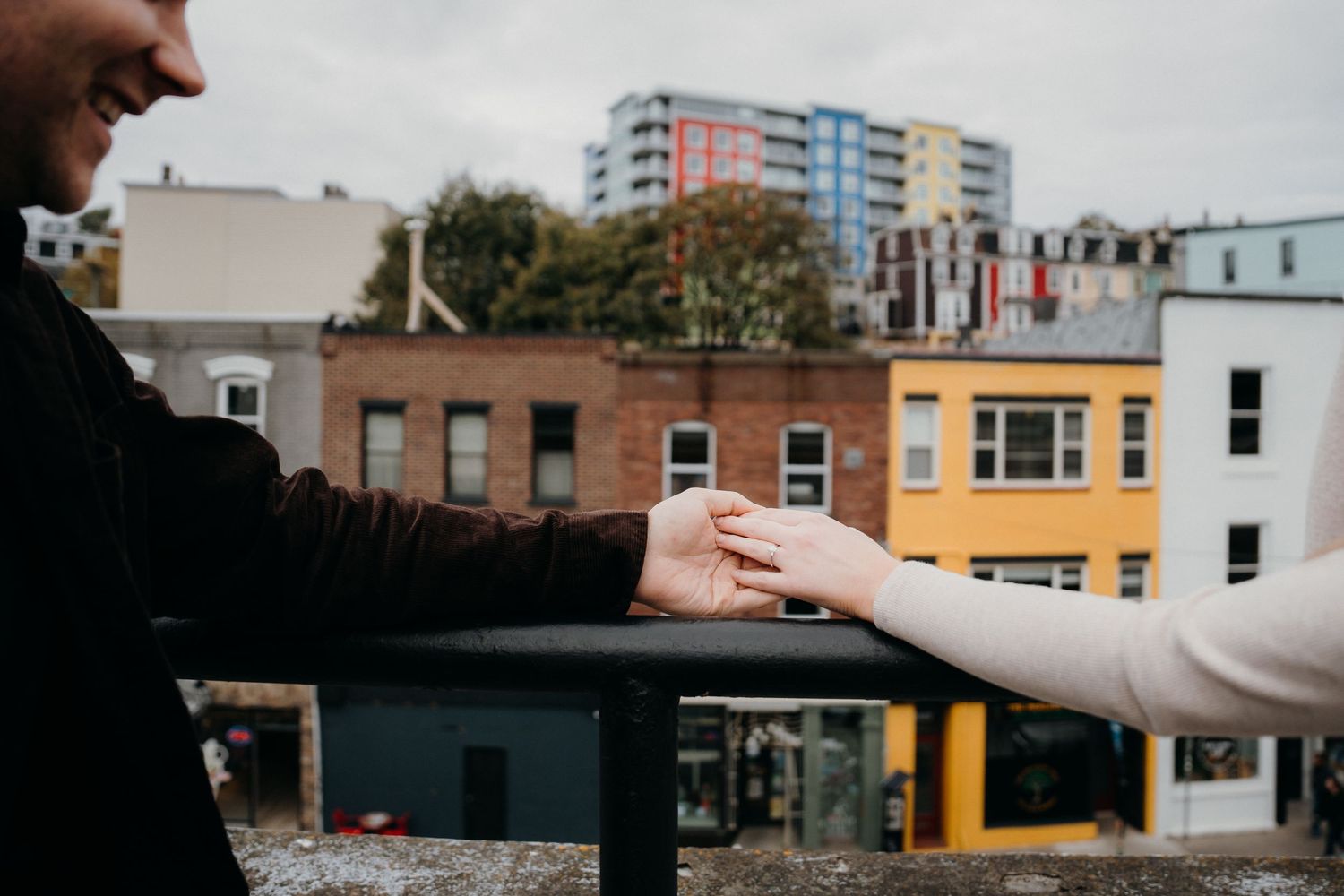 Couple's hands reaching across with urban skyline and buildings in view.