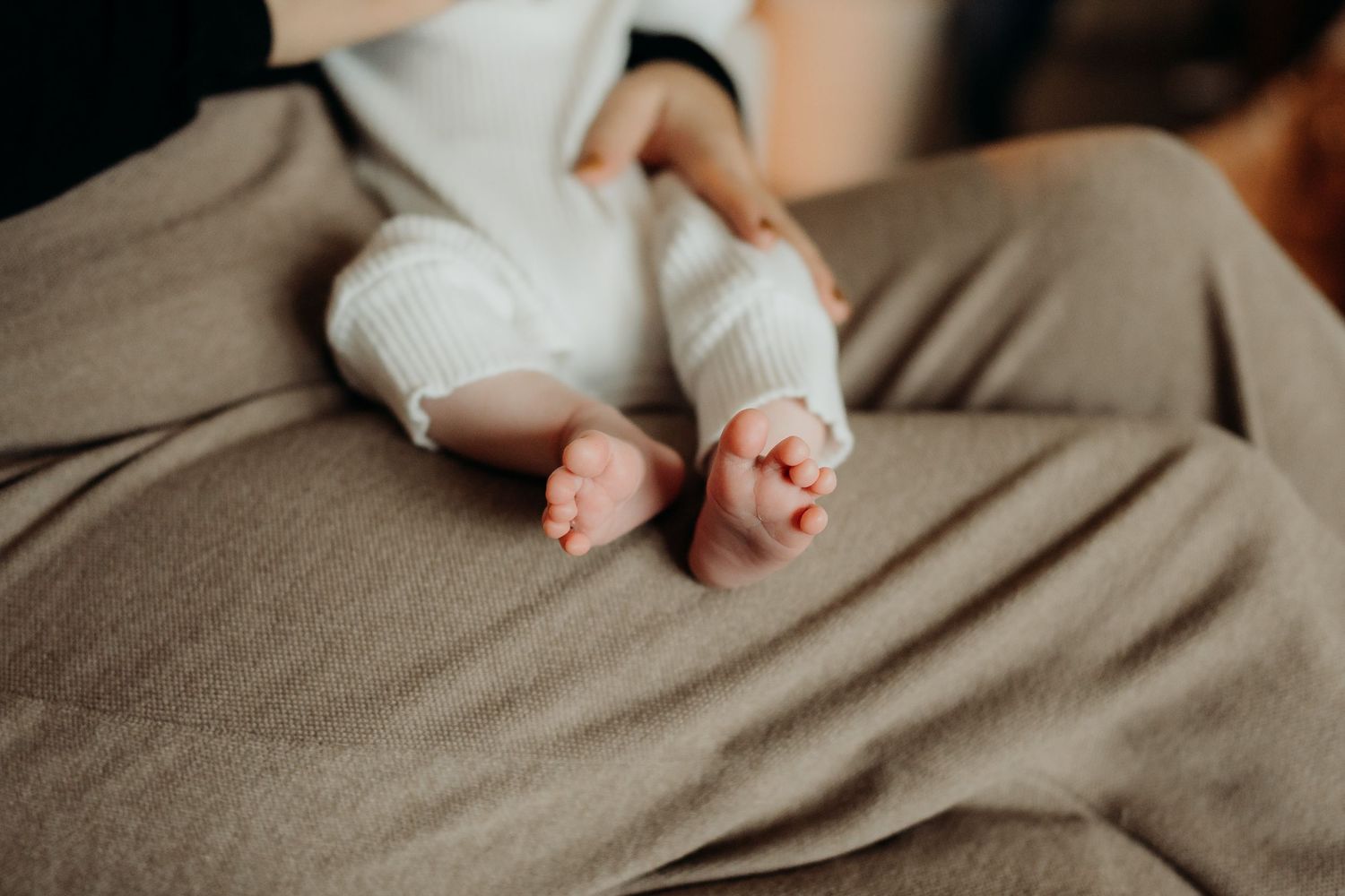 Tiny baby feet and toes against a textured gray blanket in natural light.