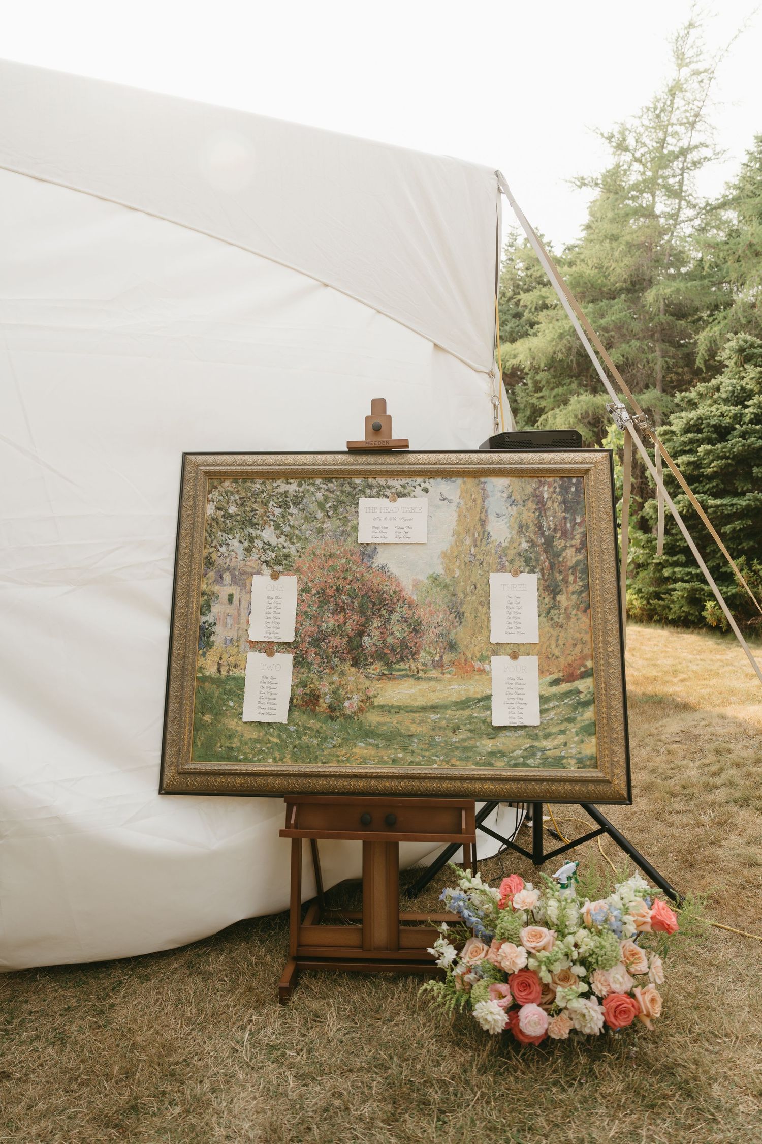 Rustic art display with floral decorations against white fabric in a garden setting.
