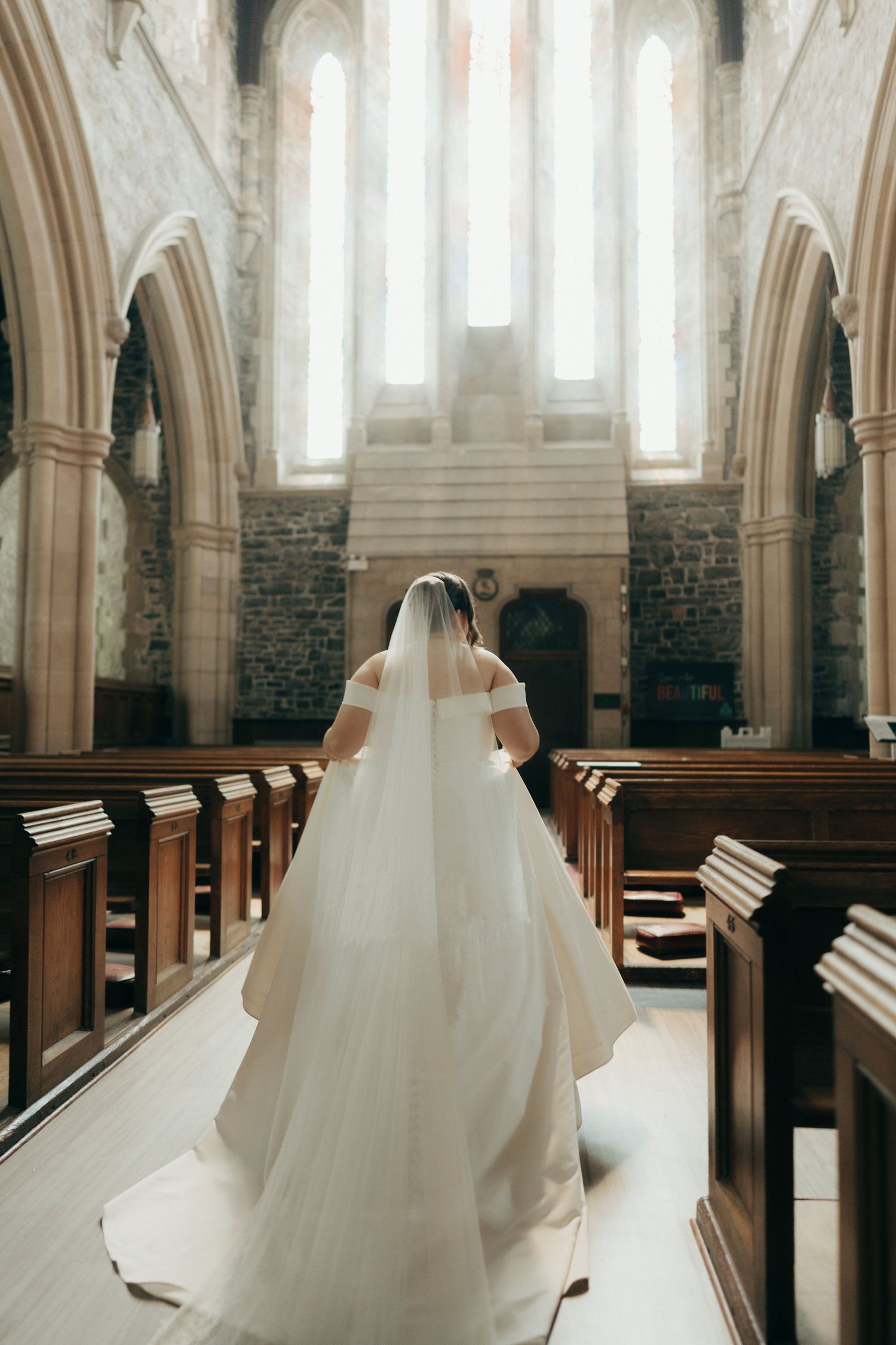 Artistic wedding photograph showcasing flowing white dress against cathedral architecture.