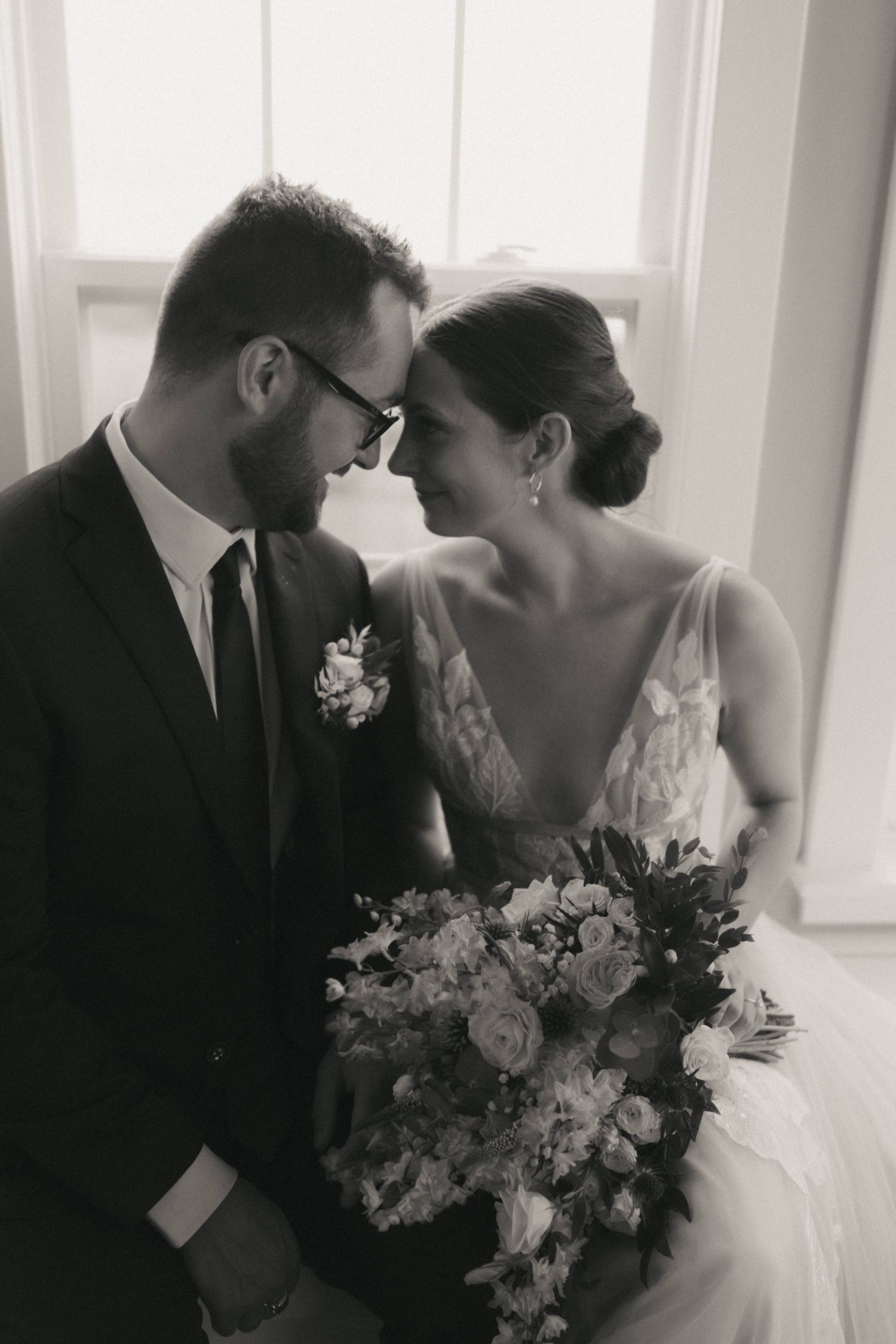 Black and white romantic wedding photos showing a bride and groom sharing intimate moments with elegant bouquets.