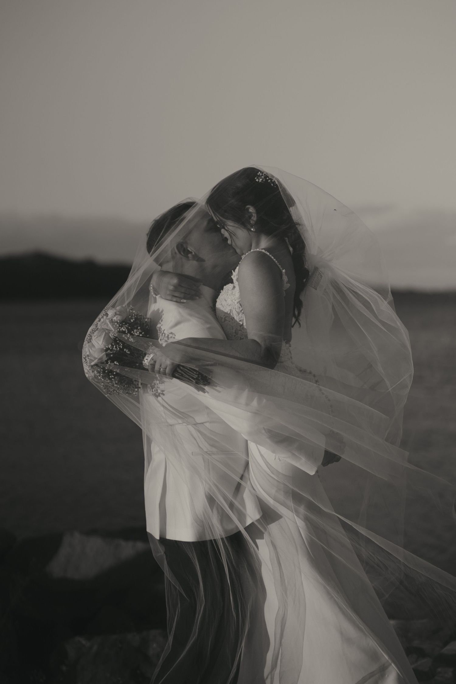 A romantic black and white wedding photo series showing a bride's veil flowing dramatically in the wind.