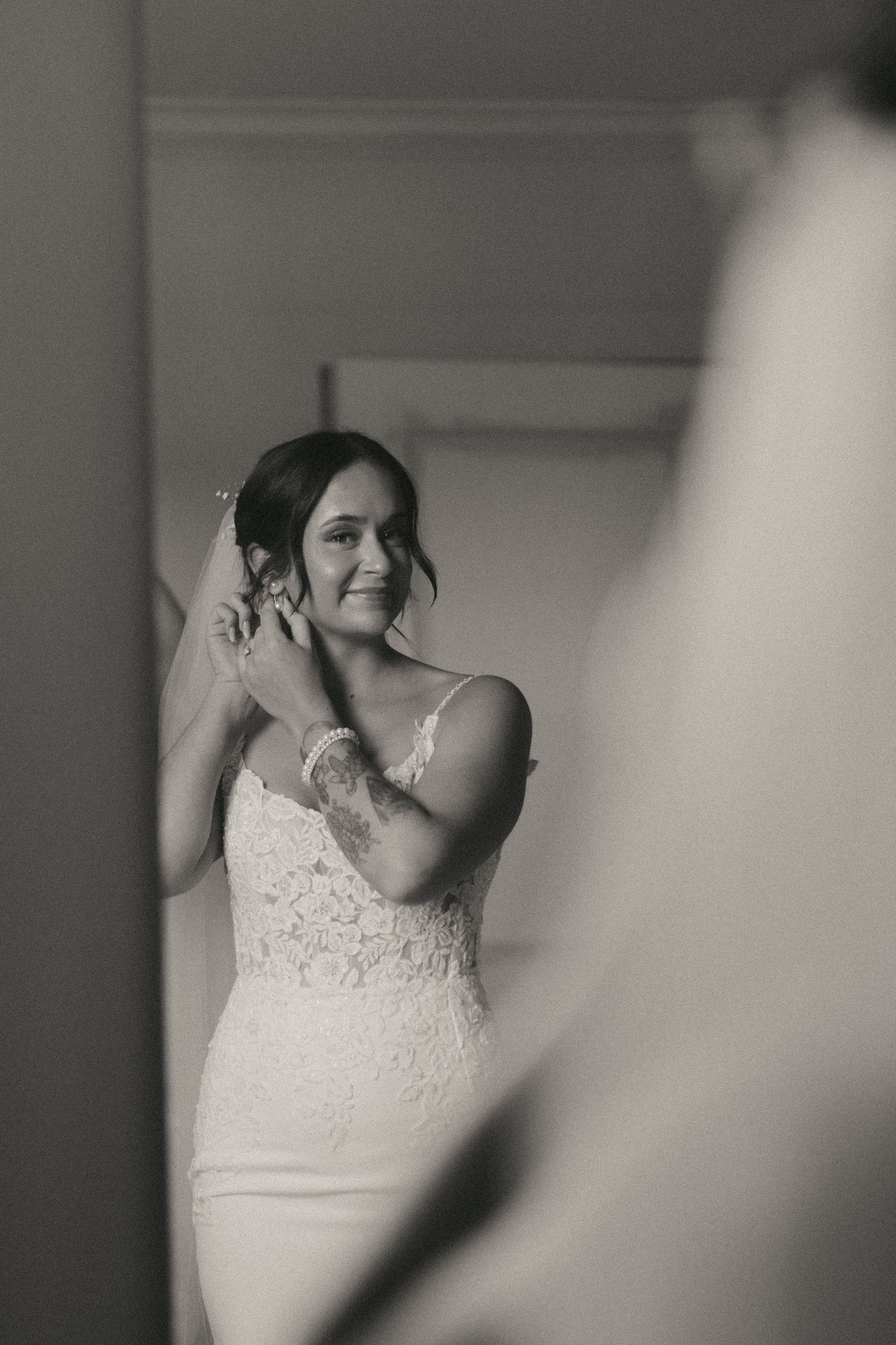 A series of black and white photographs showing a bride getting ready in a white lace wedding dress.