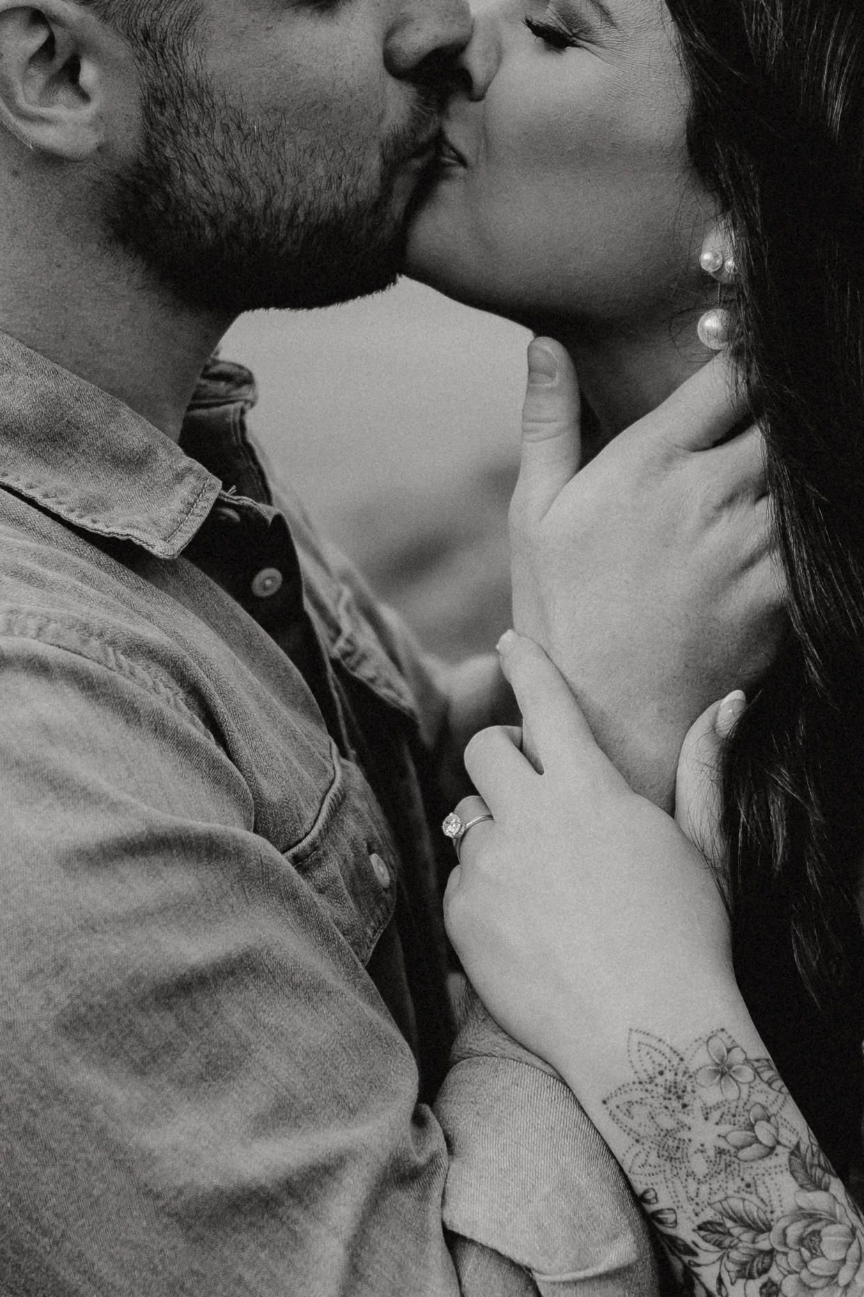 An intimate black and white portrait of a couple sharing a tender kiss.