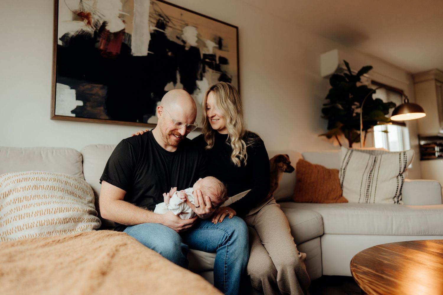 Wide angle view of family gathered on couch for newborn photo session at home.