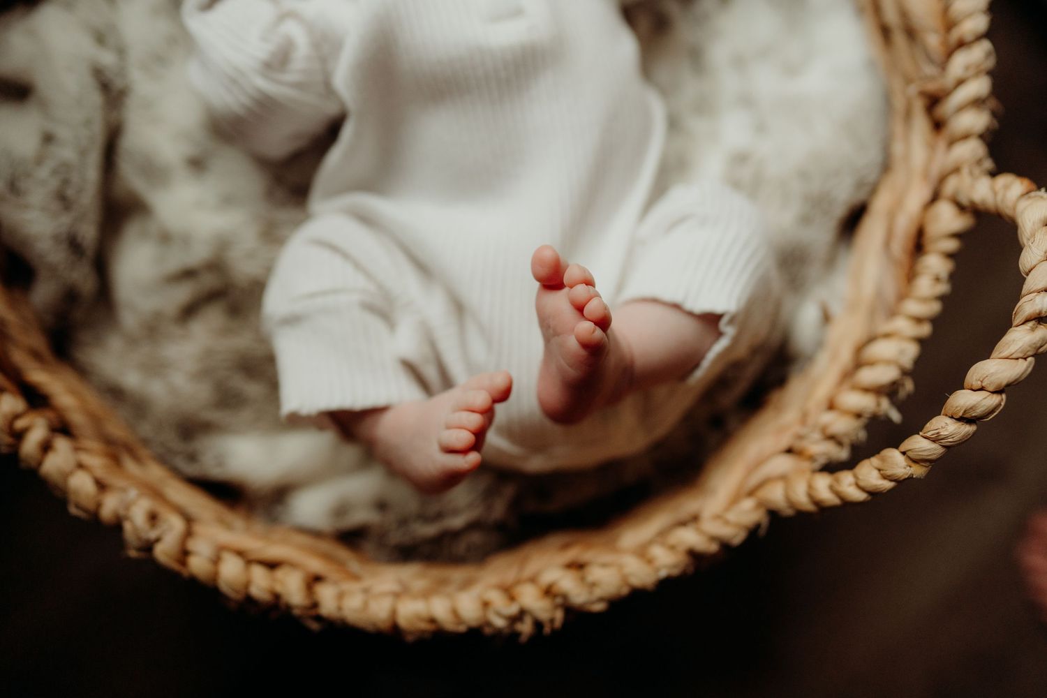 Close-up of tiny baby feet in a woven beige basket.