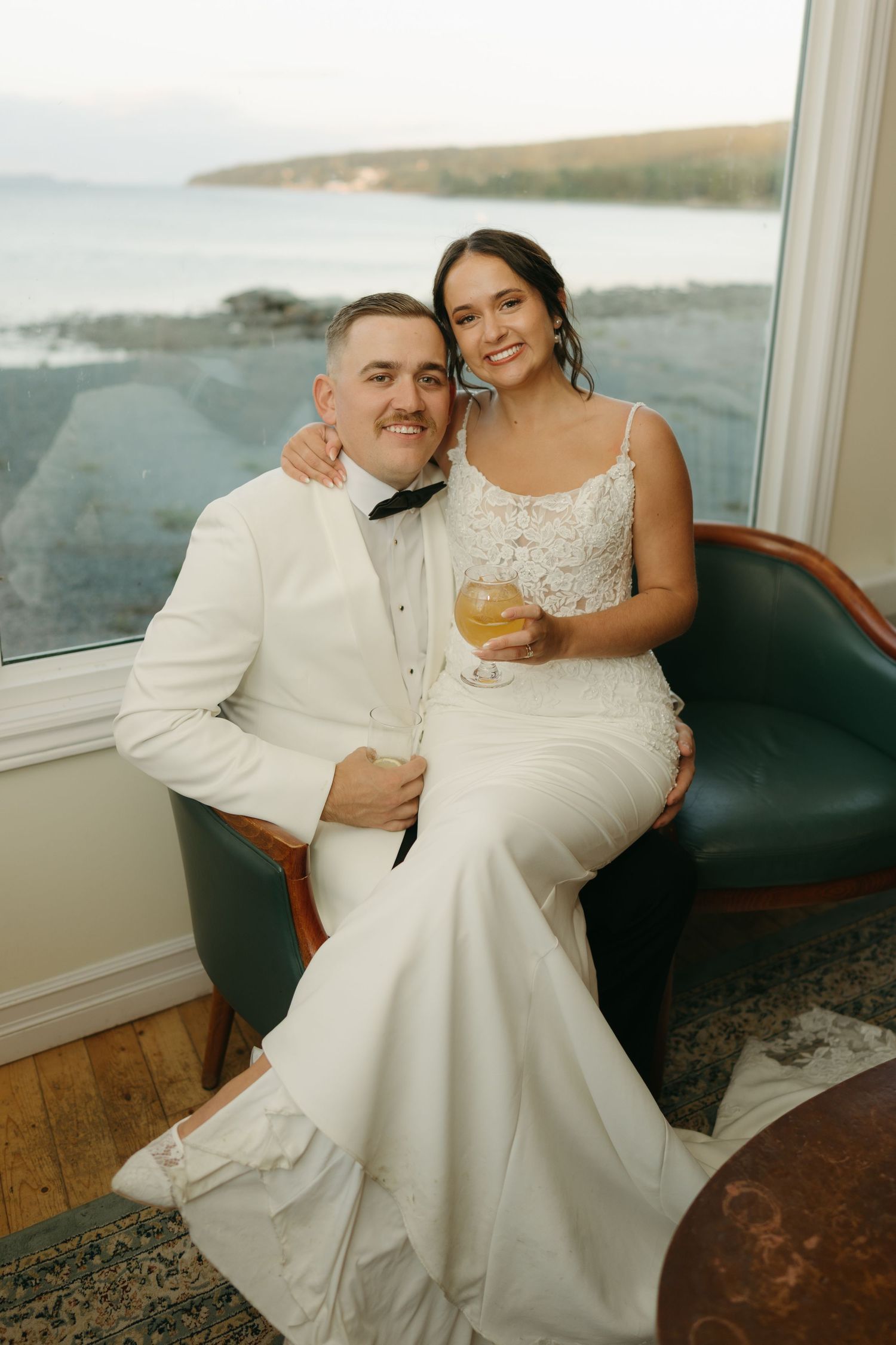 A couple shares an intimate moment together on a boat with coastal views in the background.