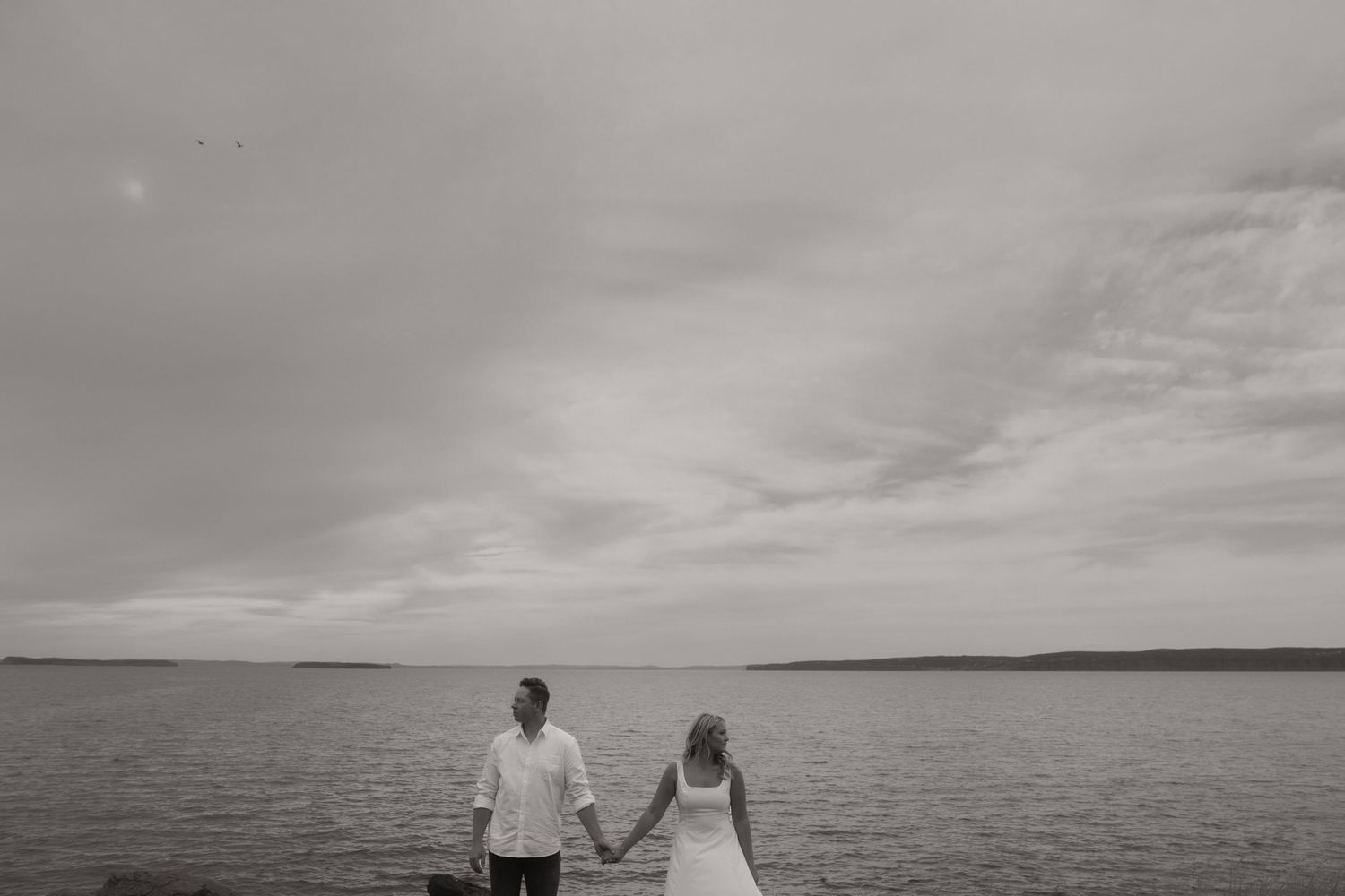 A series of black and white wedding photos showing scenic beach and ocean views with silhouettes against the horizon.