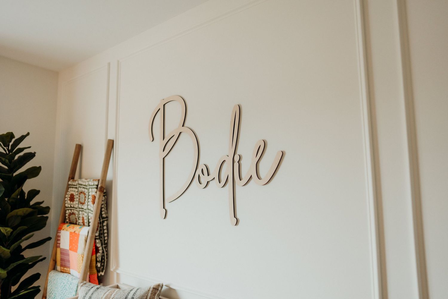 Minimalist nursery room with decorative script text on wall.