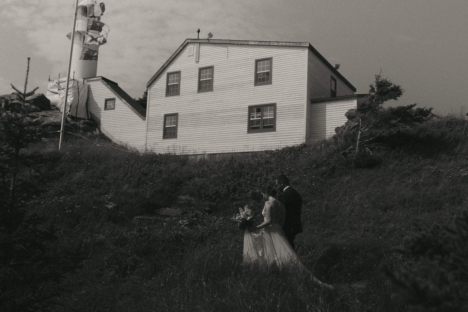 A black and white landscape featuring old farmhouses along a rural hillside.