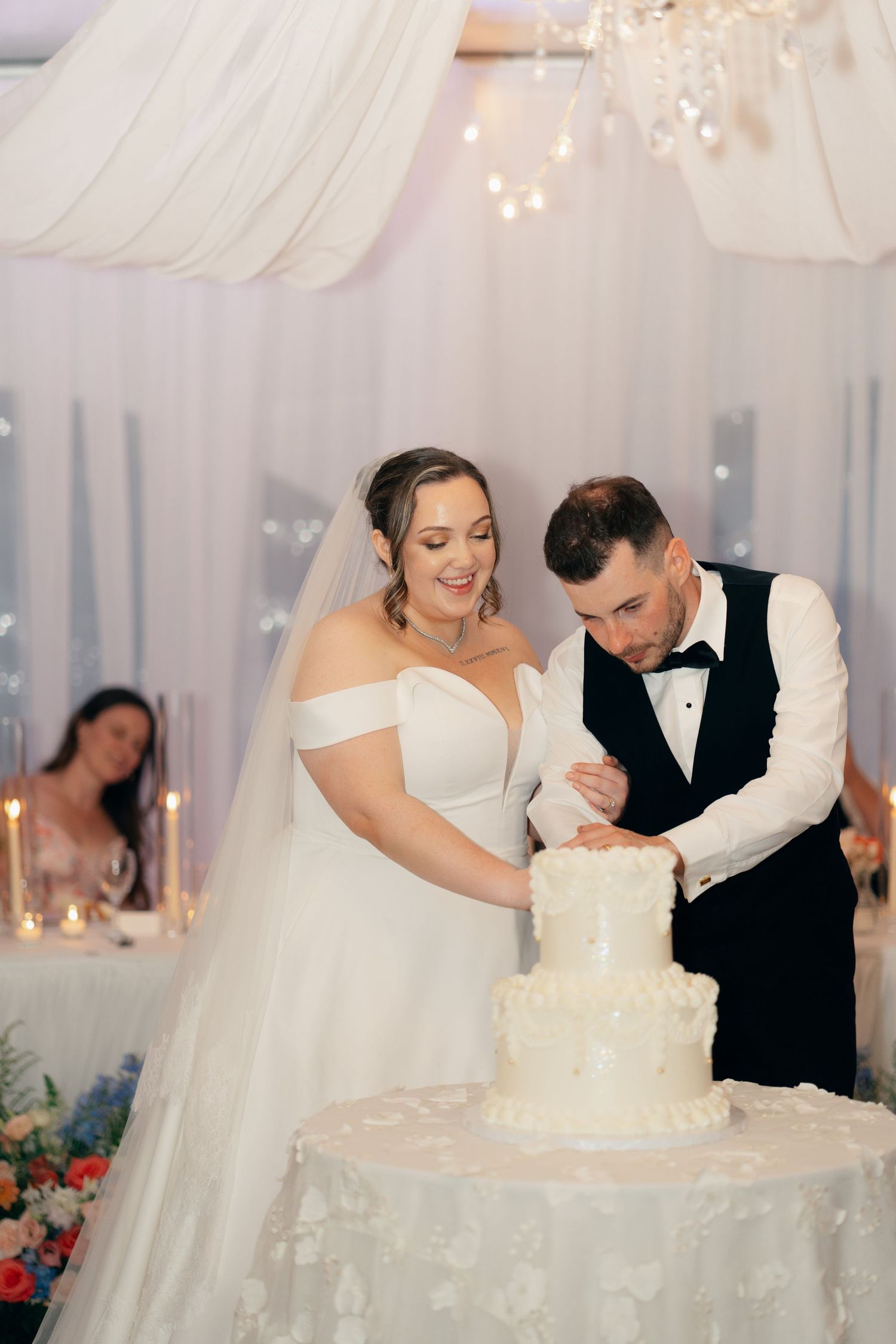 A couple participates in their wedding cake cutting ceremony in an elegantly decorated reception space.