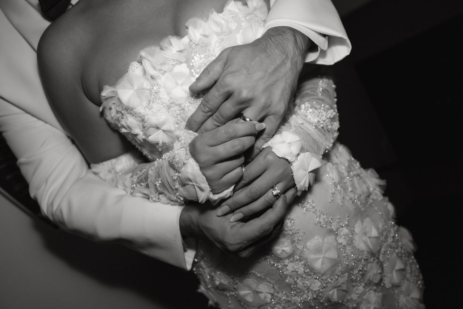 Close-up shot of hands delicately adjusting a white lace wedding dress detail.