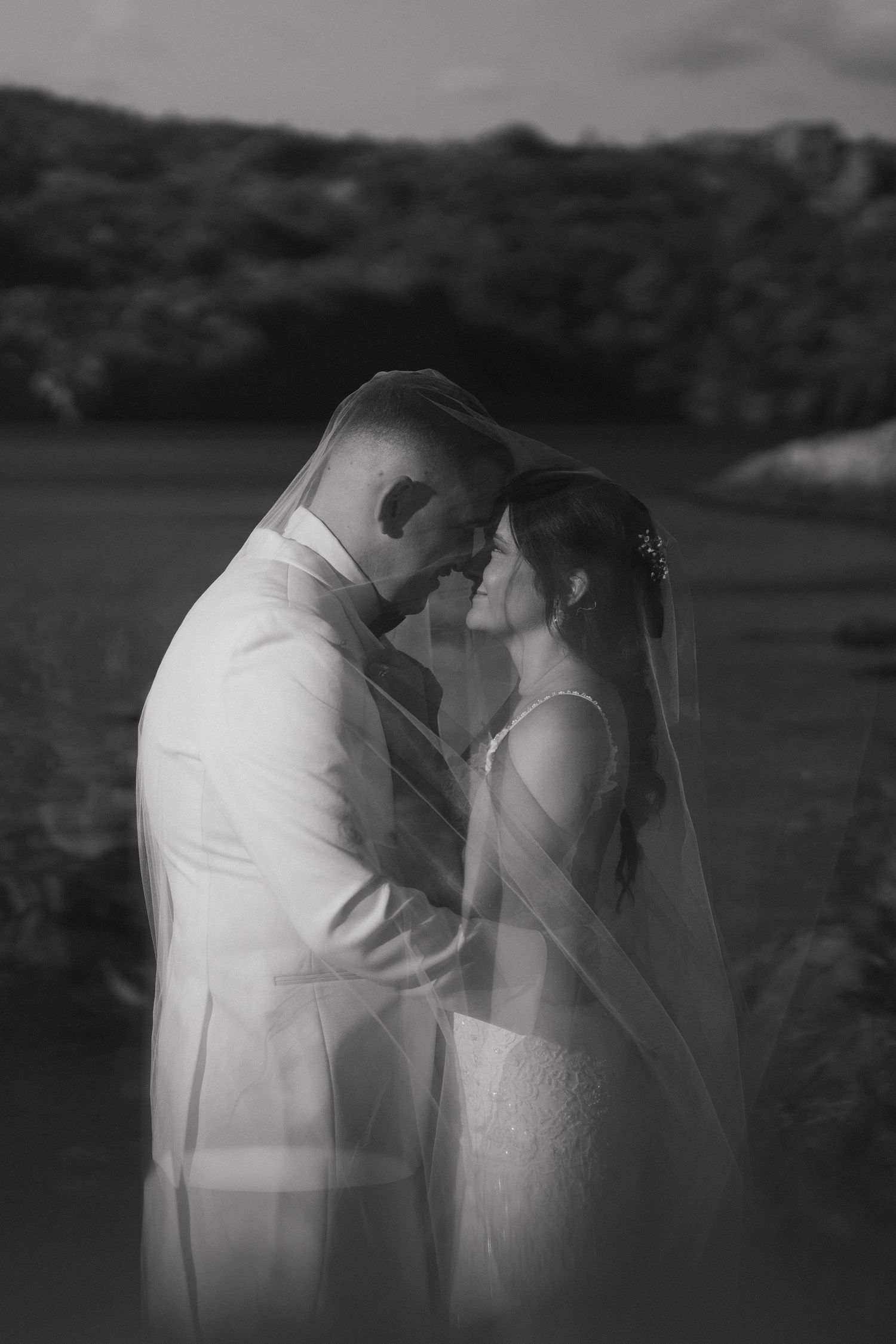 A romantic black and white photo series showing a couple in wedding attire embracing in different poses outdoors.