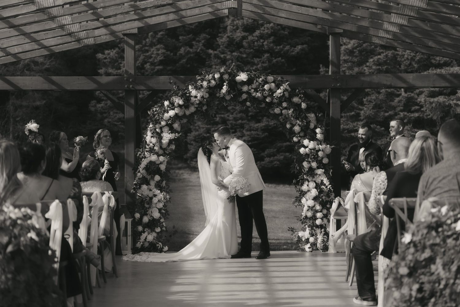 A sequence of black and white wedding ceremony photos showing couples dancing and celebrating at an outdoor reception.