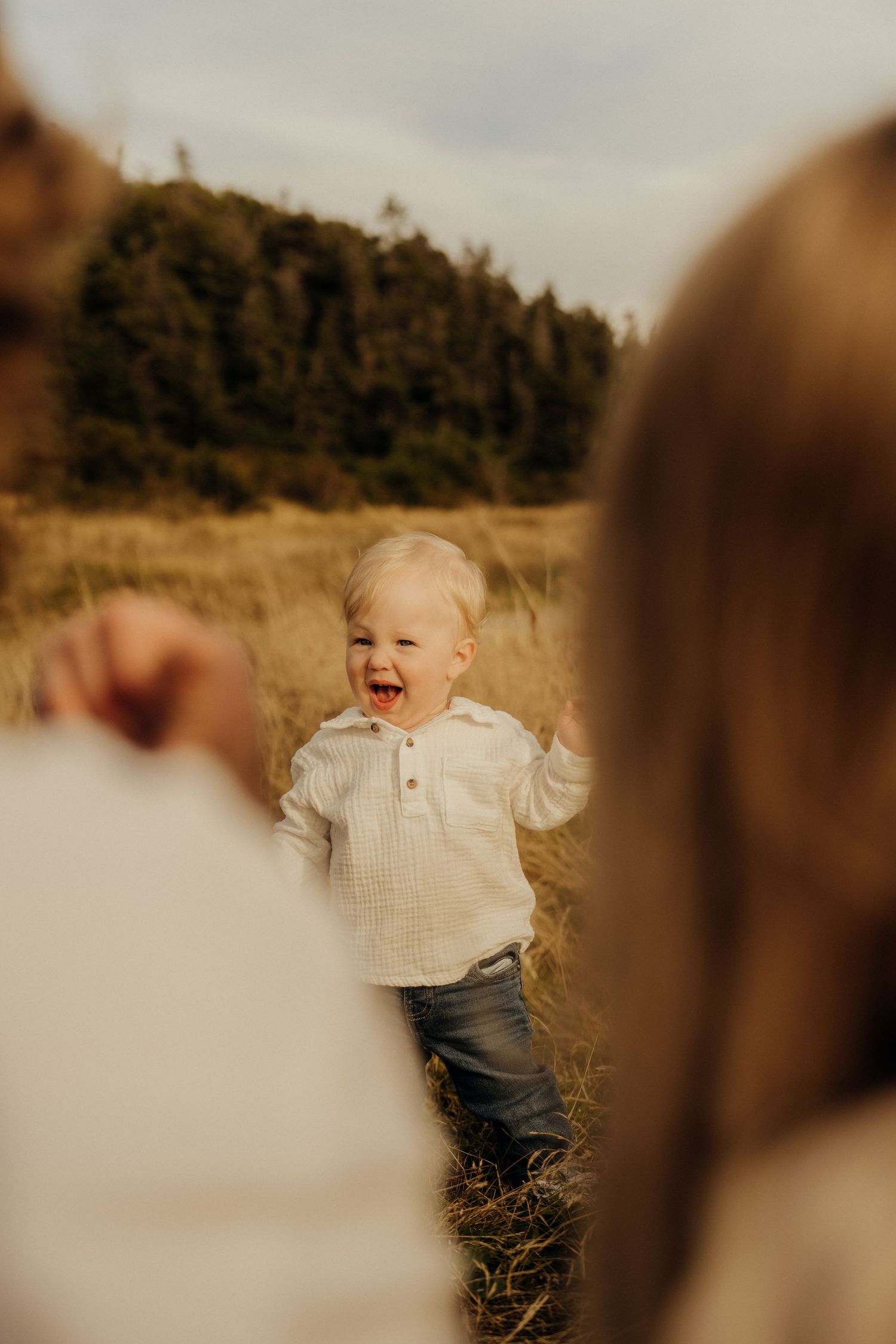 A series of five progressive photos showing a small child laughing and jumping in an outdoor field at sunset.