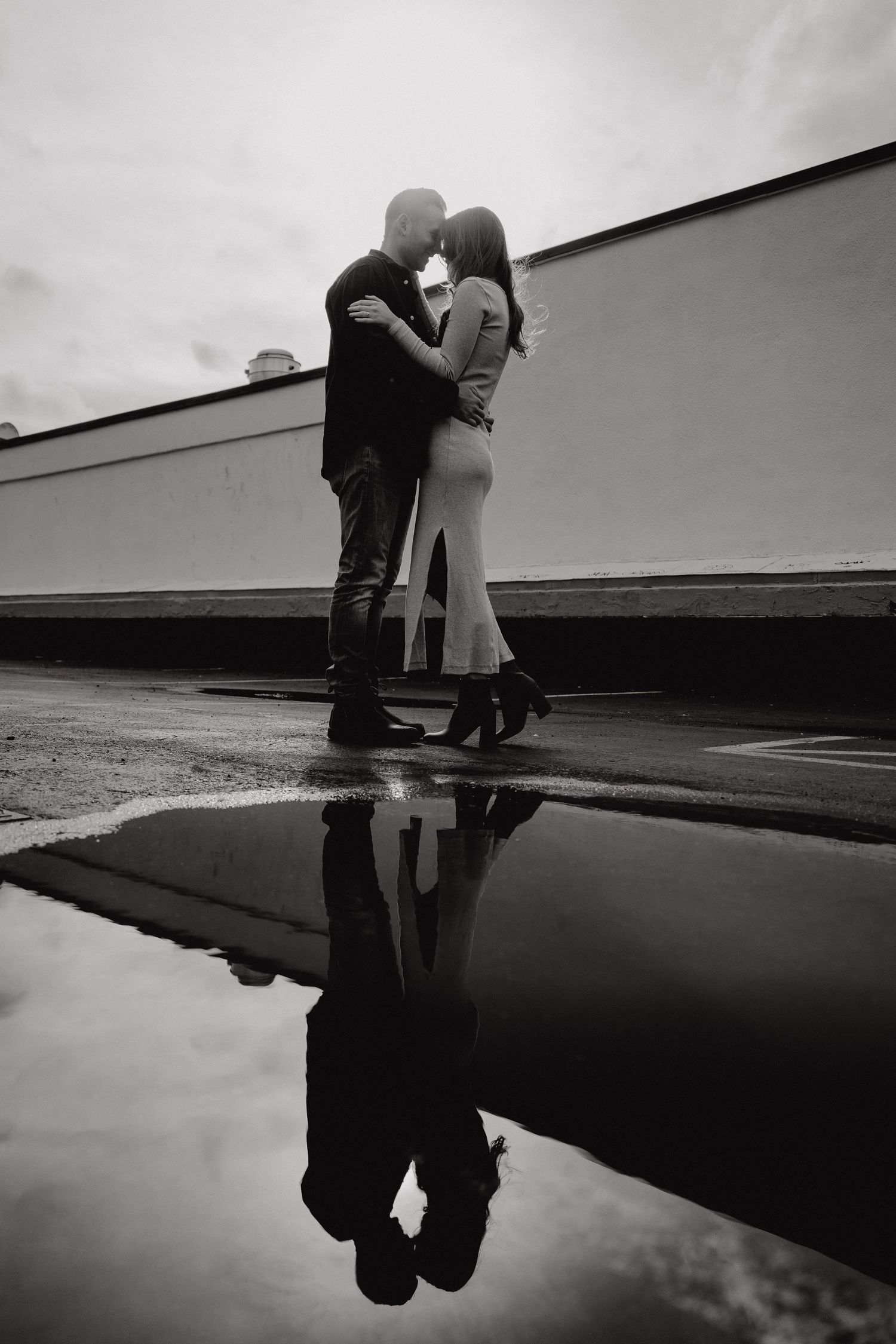Artistic black and white photo of a couple's silhouette reflected in standing water.