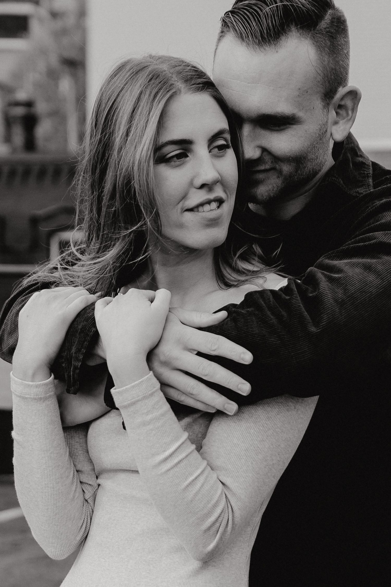 Intimate close-up of couple's tender embrace in monochrome on city rooftop.