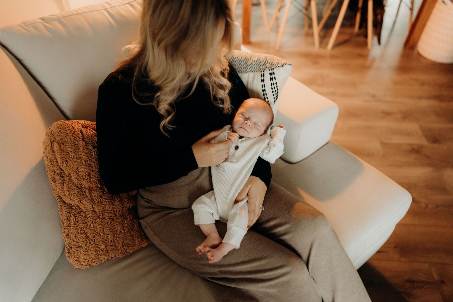 Indoor lifestyle scene with a baby in white clothing on a wooden floor.