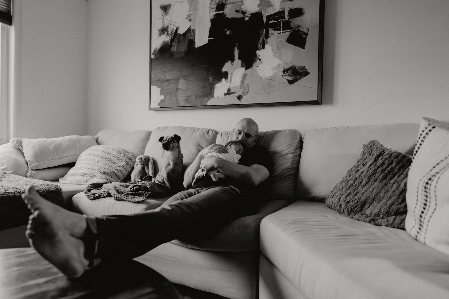 Black and white photograph shows a person lounging on a plush gray couch.