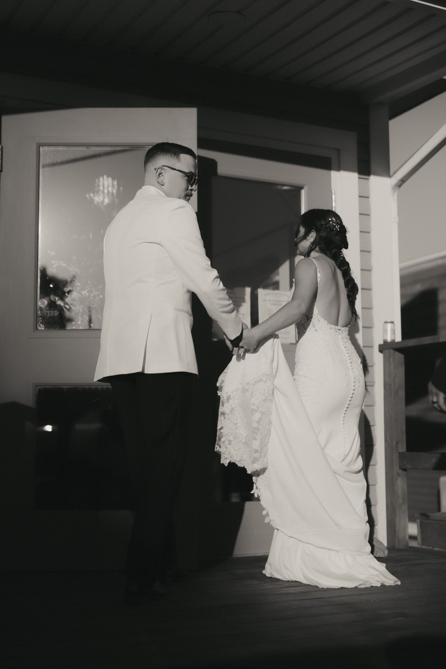 A series of black and white photos showing a couple in wedding attire walking through a dimly lit hallway.