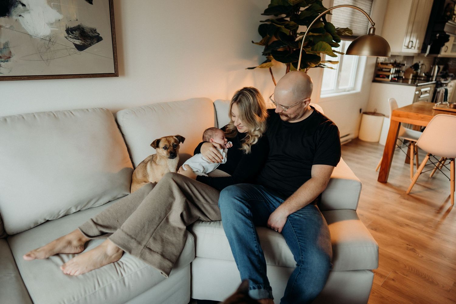 Modern living room scene with people and dog sharing quiet moments on gray sofa.
