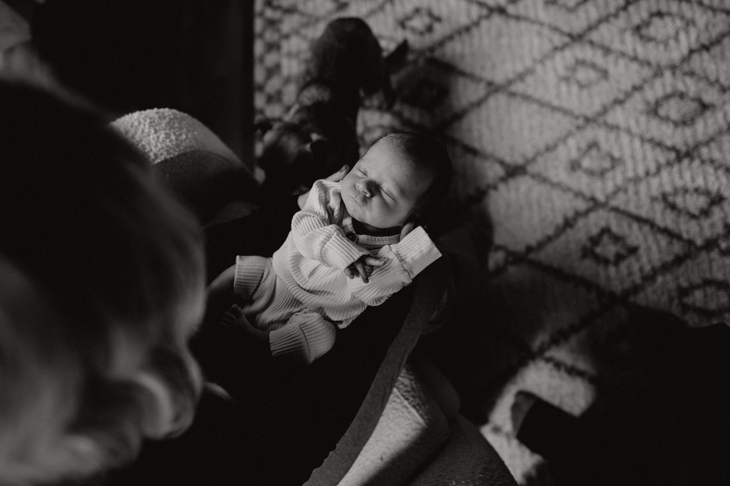 Dramatic shadows fall across infant and patterned rug in lifestyle portrait.