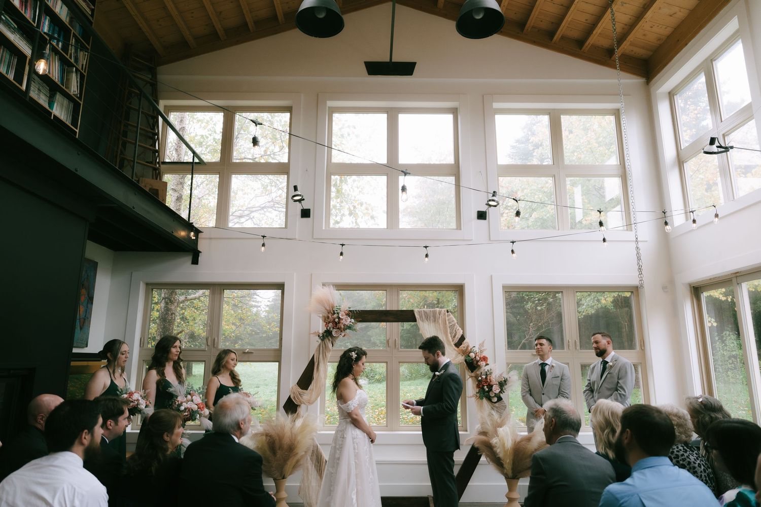 Wedding celebration in a rustic venue with wooden beams and large windows.