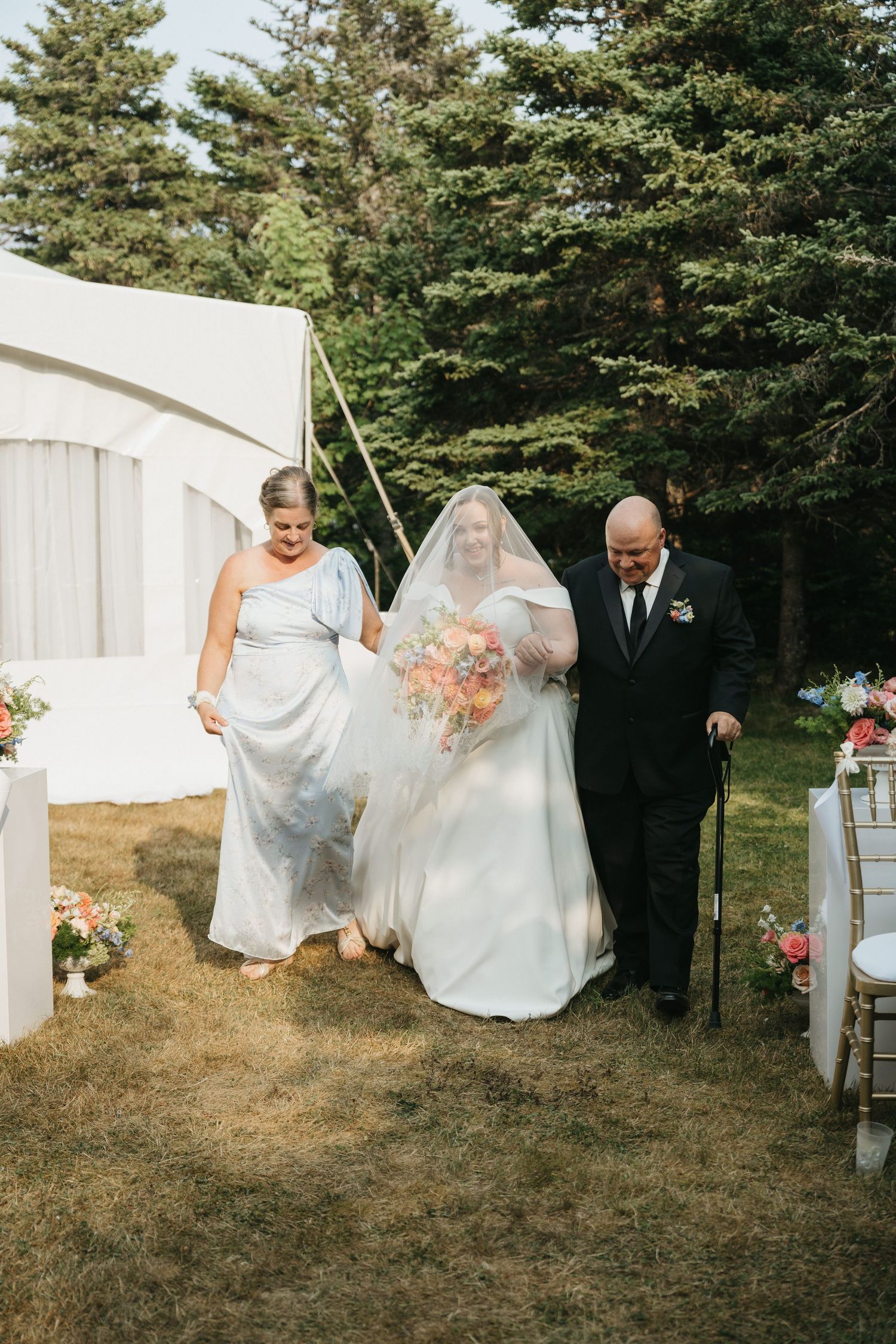 Candid moment of guests moving between white tents at an outdoor wedding celebration.