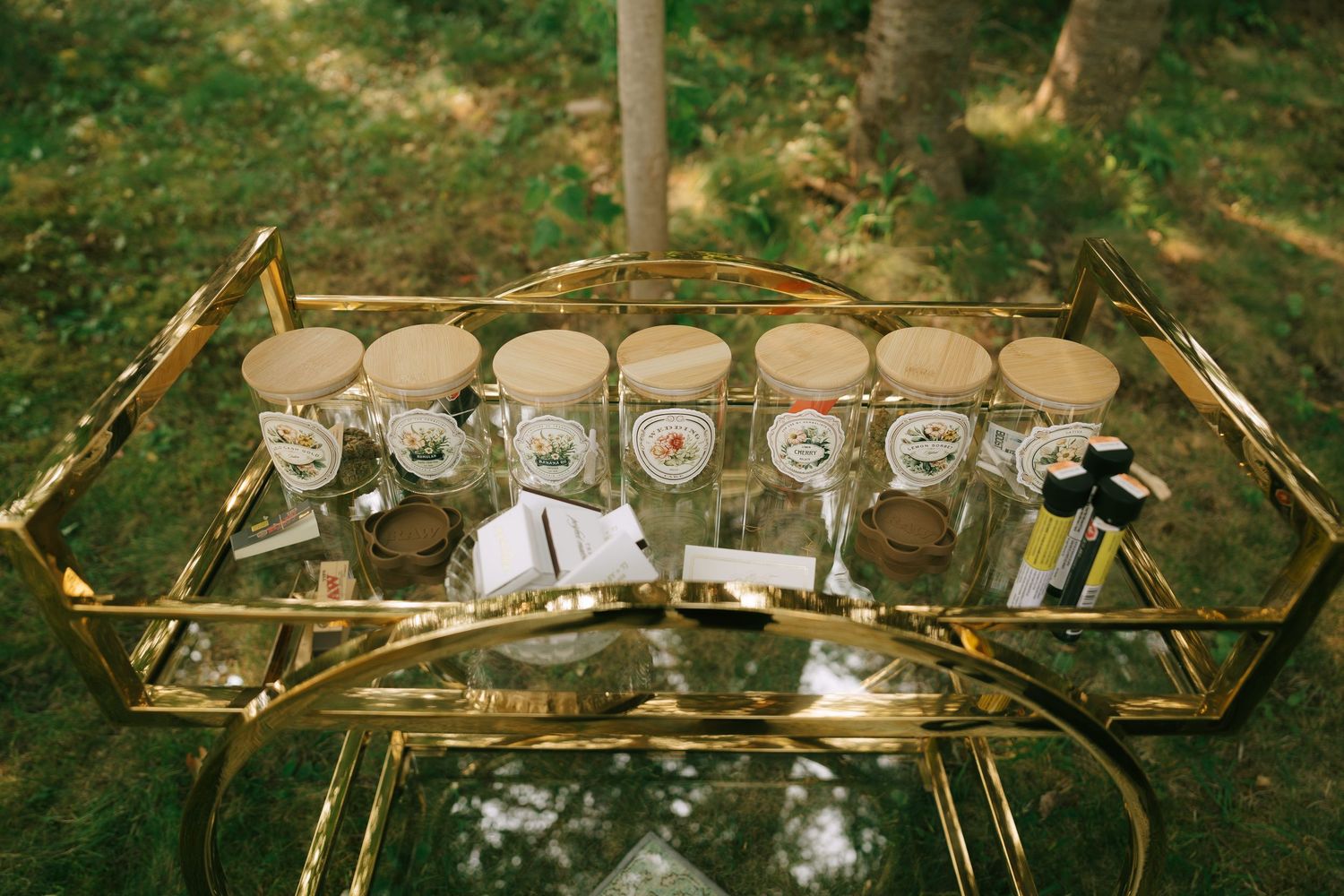 Gold geometric display shelf showcasing vintage teacups and tableware outdoors.