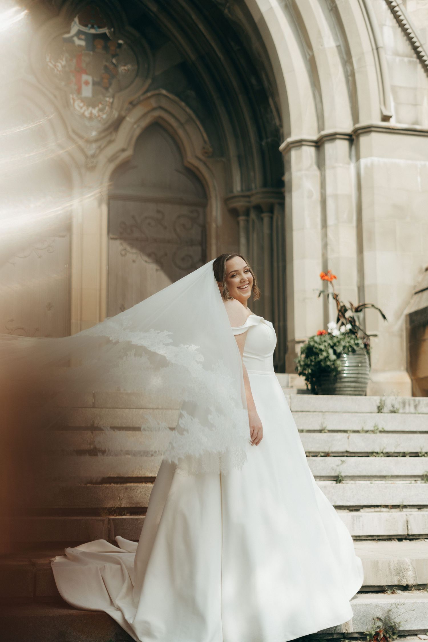 A billowing white wedding dress captured on stone church steps in soft light.