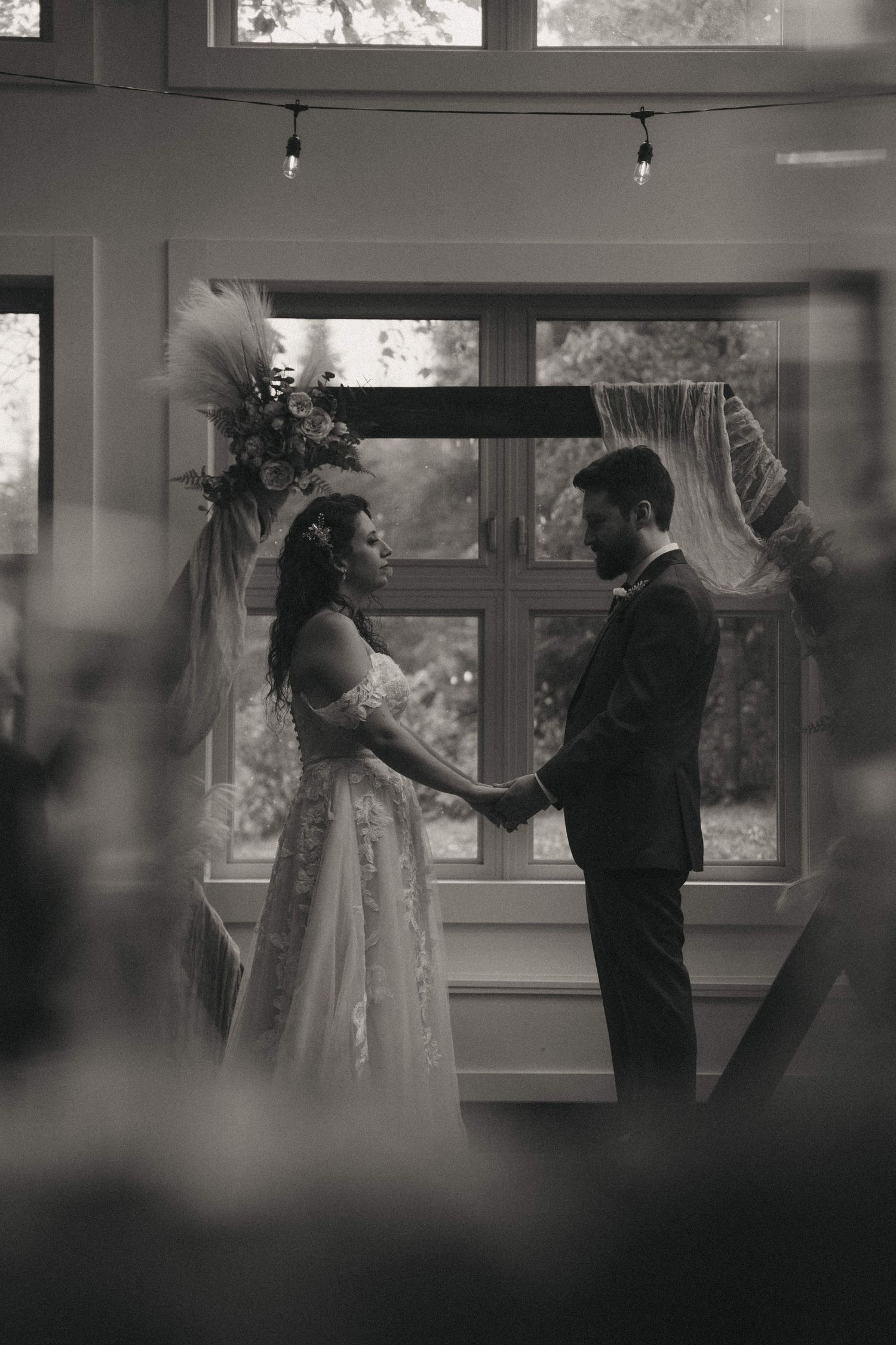 Wedding couple dances in a sunlit room with large windows creating a romantic atmosphere.