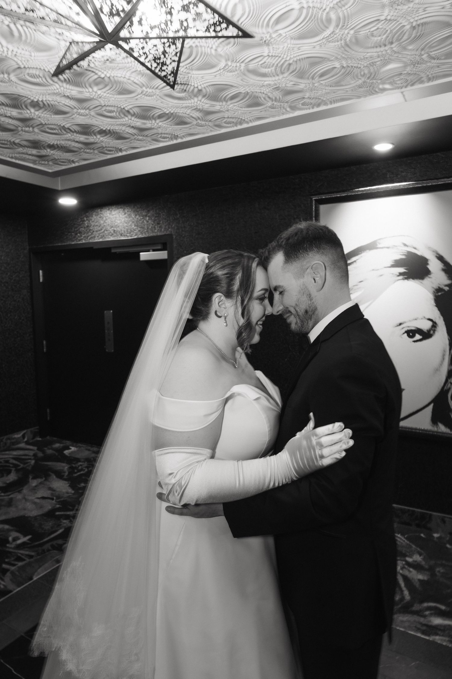 Indoor wedding portraits under ornate ceiling with dramatic black and white lighting.