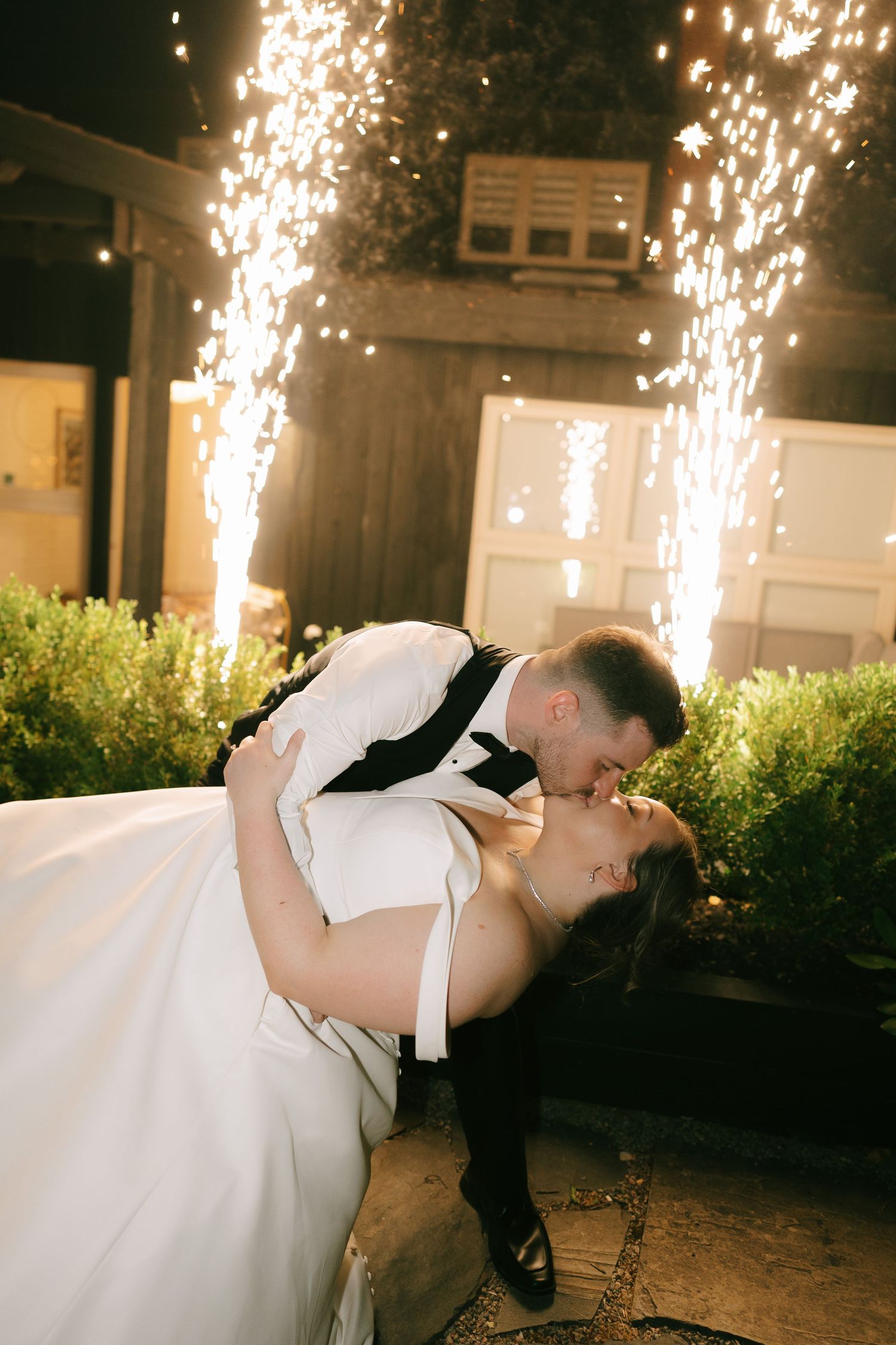 Romantic nighttime wedding dance with cascading sparkler fountains in background.