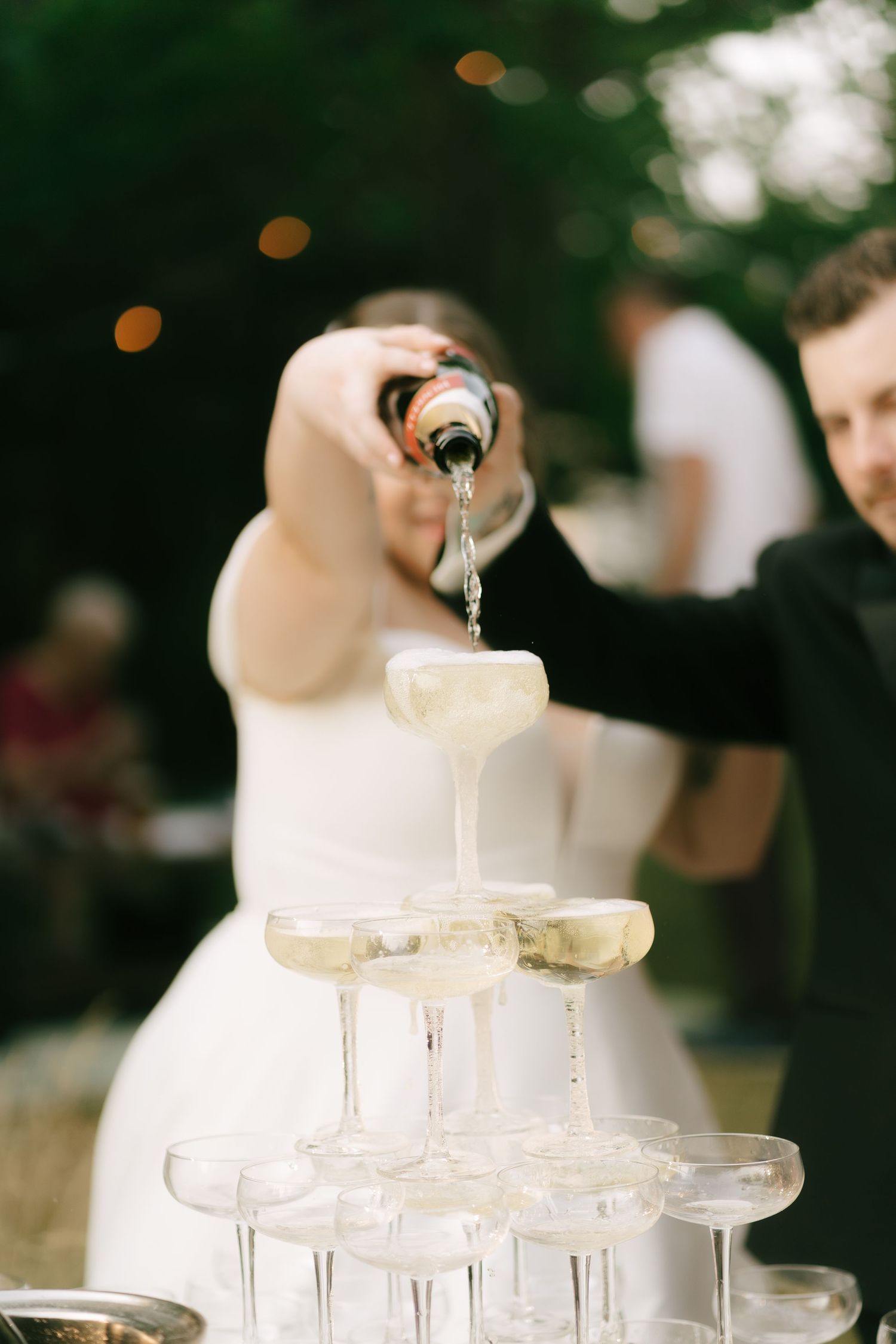 Champagne flowing down a crystal glass tower display at an elegant outdoor event.