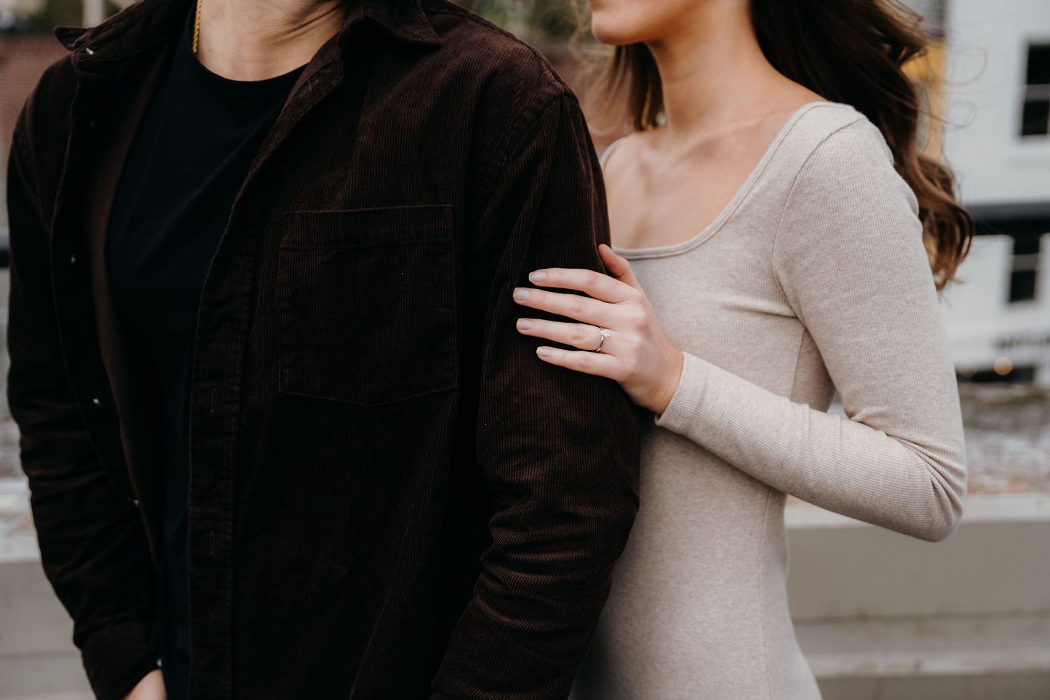 Couple in casual attire sharing a close moment against urban architecture.