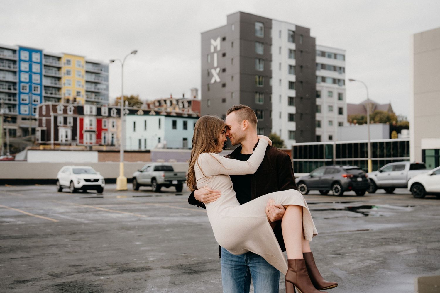 A romantic dance sequence taking place in an urban parking lot with apartment buildings in the background.