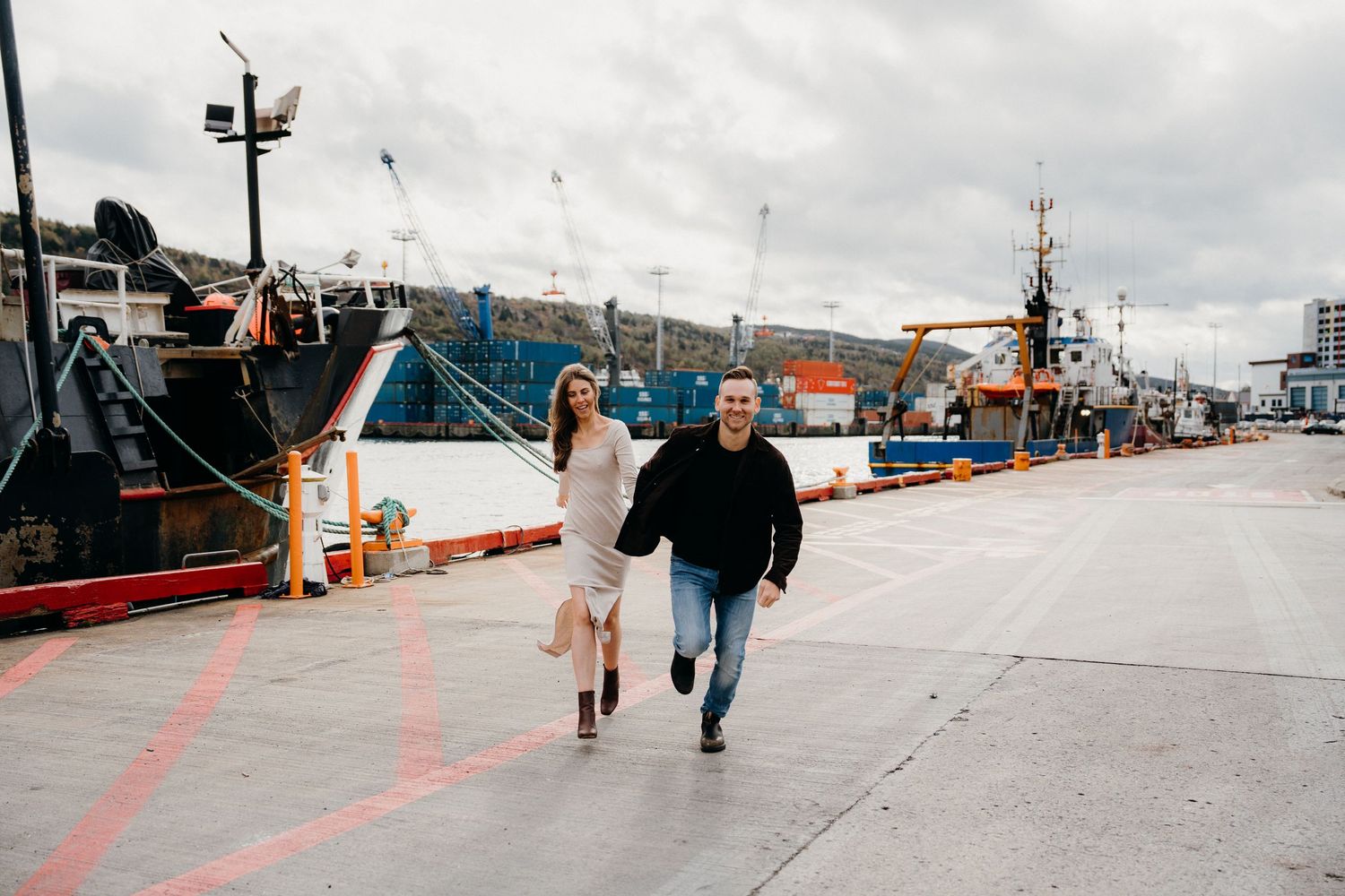 Two people walking along a maritime dock under overcast skies.