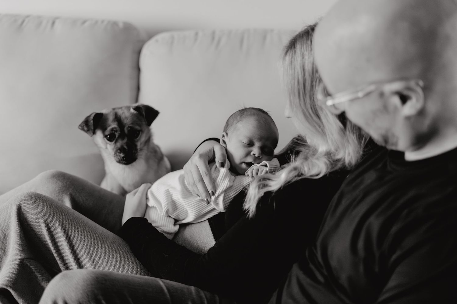 Black and white photo of a tender family moment on a living room sofa.