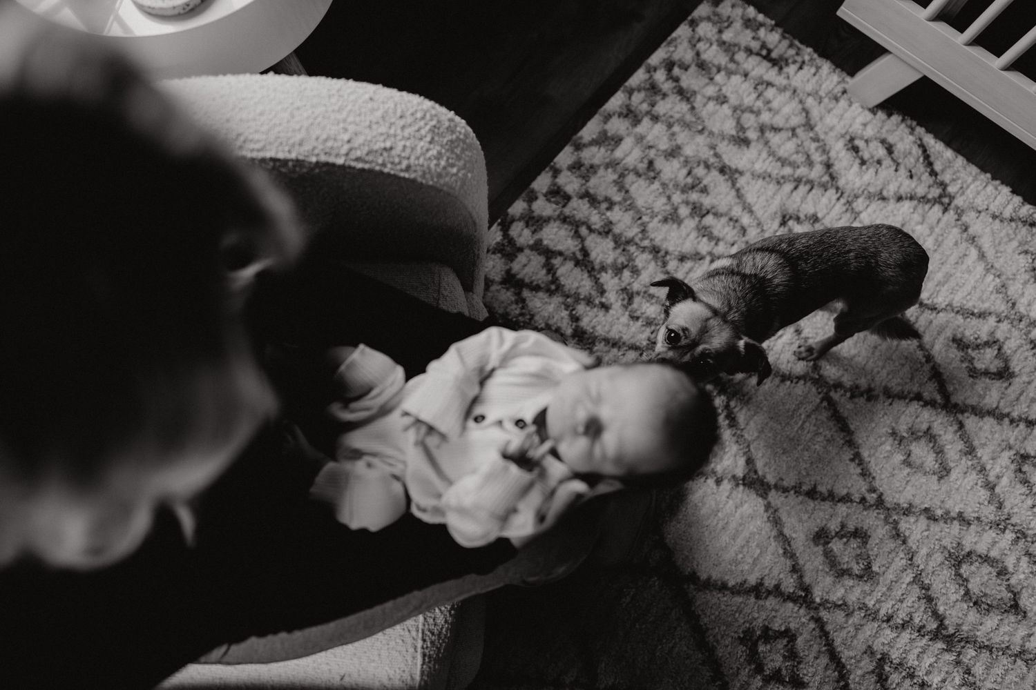 Artistic black and white photograph of baby resting on geometric patterned carpet.