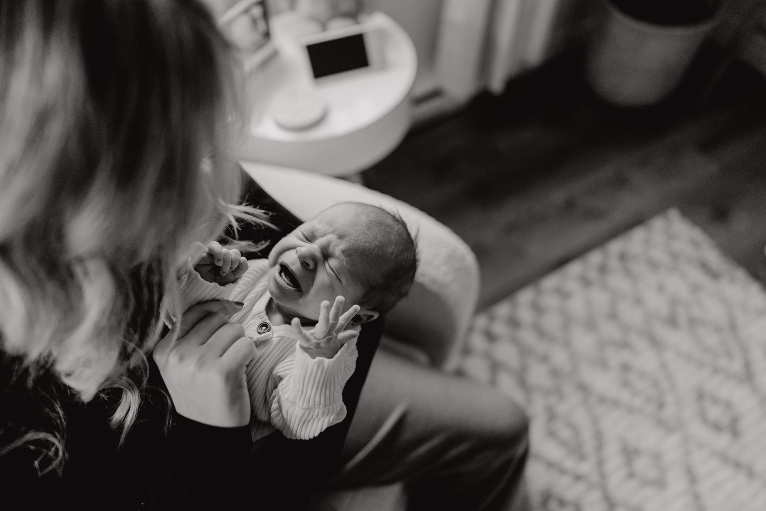 Black and white image showing tender moments in a baby's nursery room.