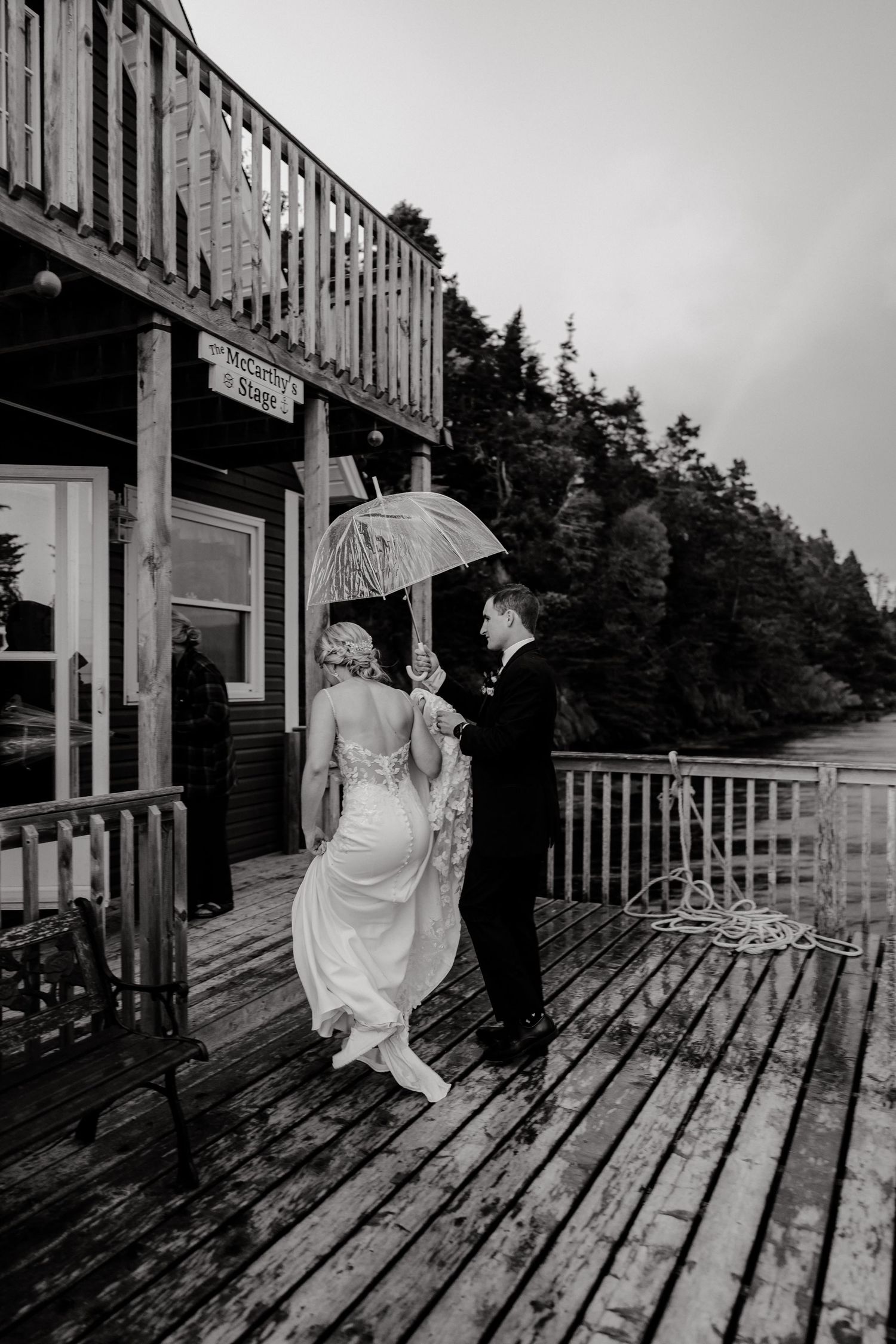 Black and white wedding photos on rustic wooden boardwalk with umbrella.