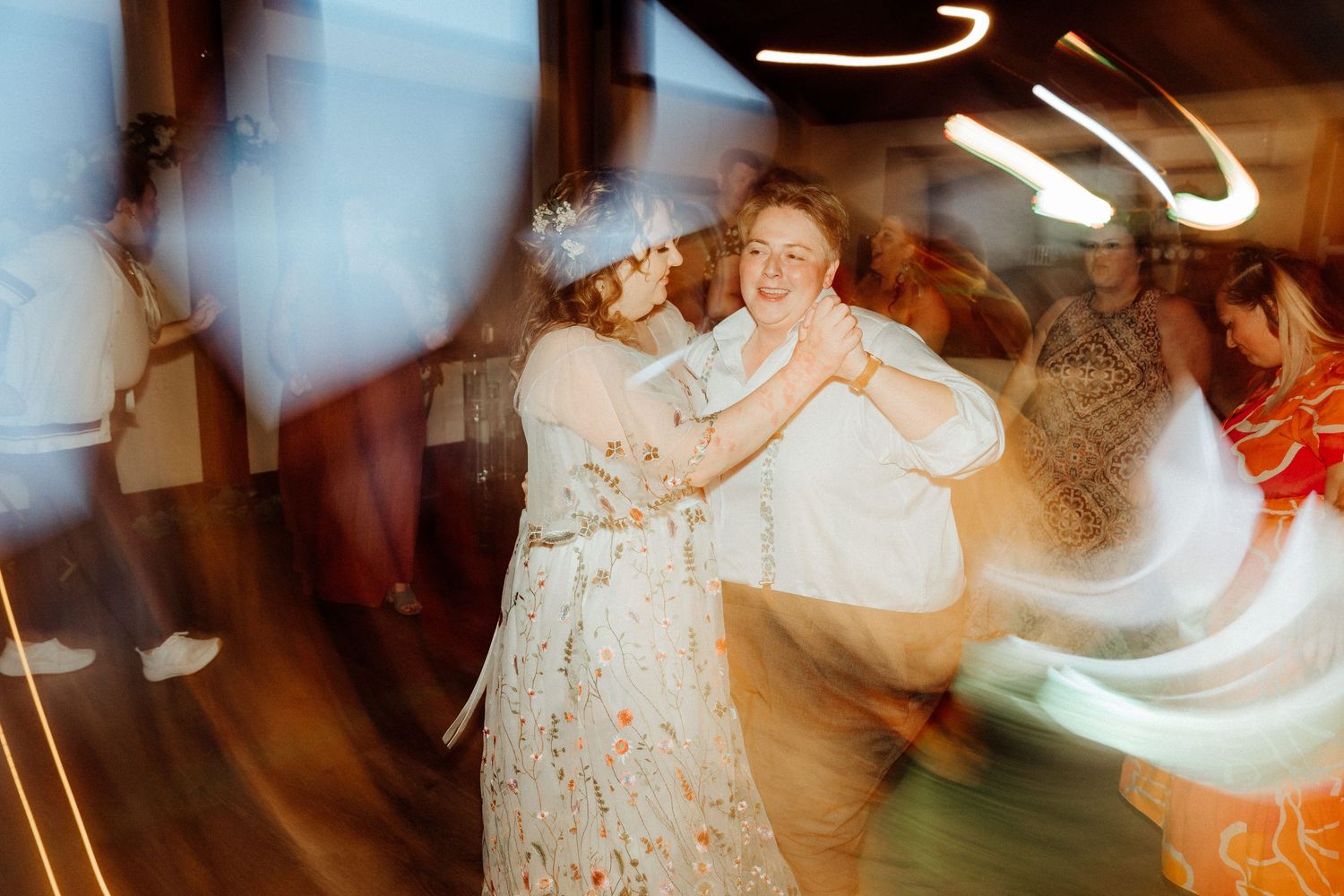 Abstract motion blur captures dancing figures in white creating ethereal light trails.
