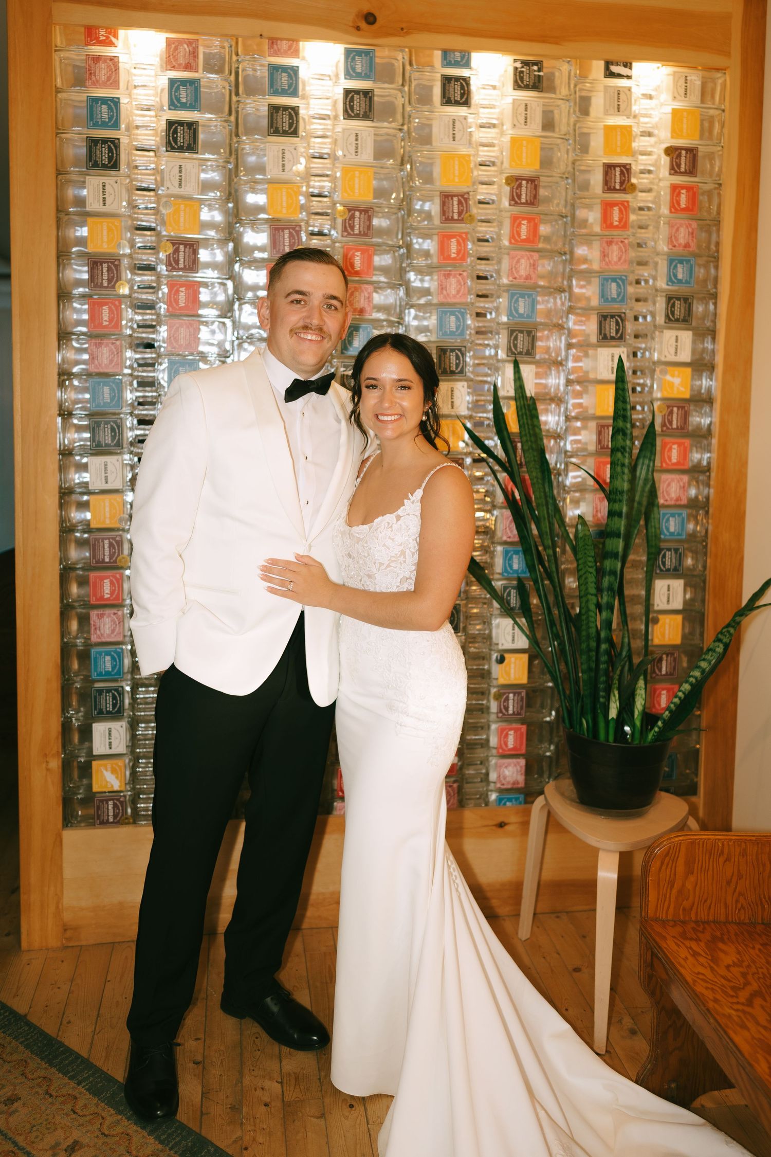 Three similar wedding photos showing a couple posing in formal attire against a wall with illuminated display cases.