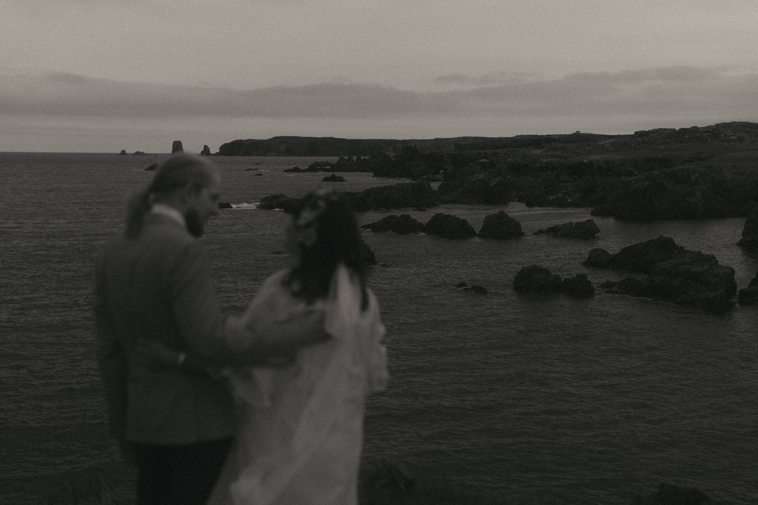 A black and white film strip showing multiple frames of a rocky coastal landscape with ocean waves.
